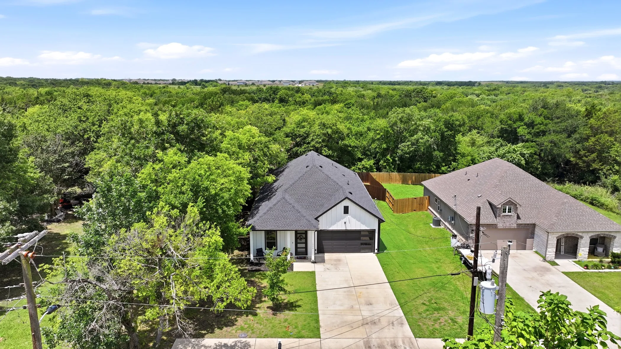 Newly constructed residence featuring a dark shingle roof, white siding, and a dark garage door