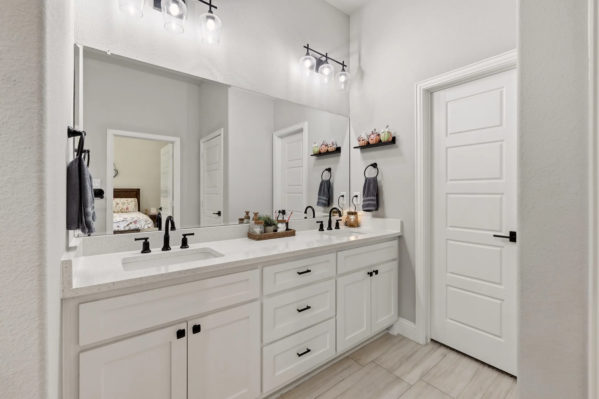Double vanity featuring white cabinetry with matte black hardware, dual undermount sinks, and a light-toned countertop