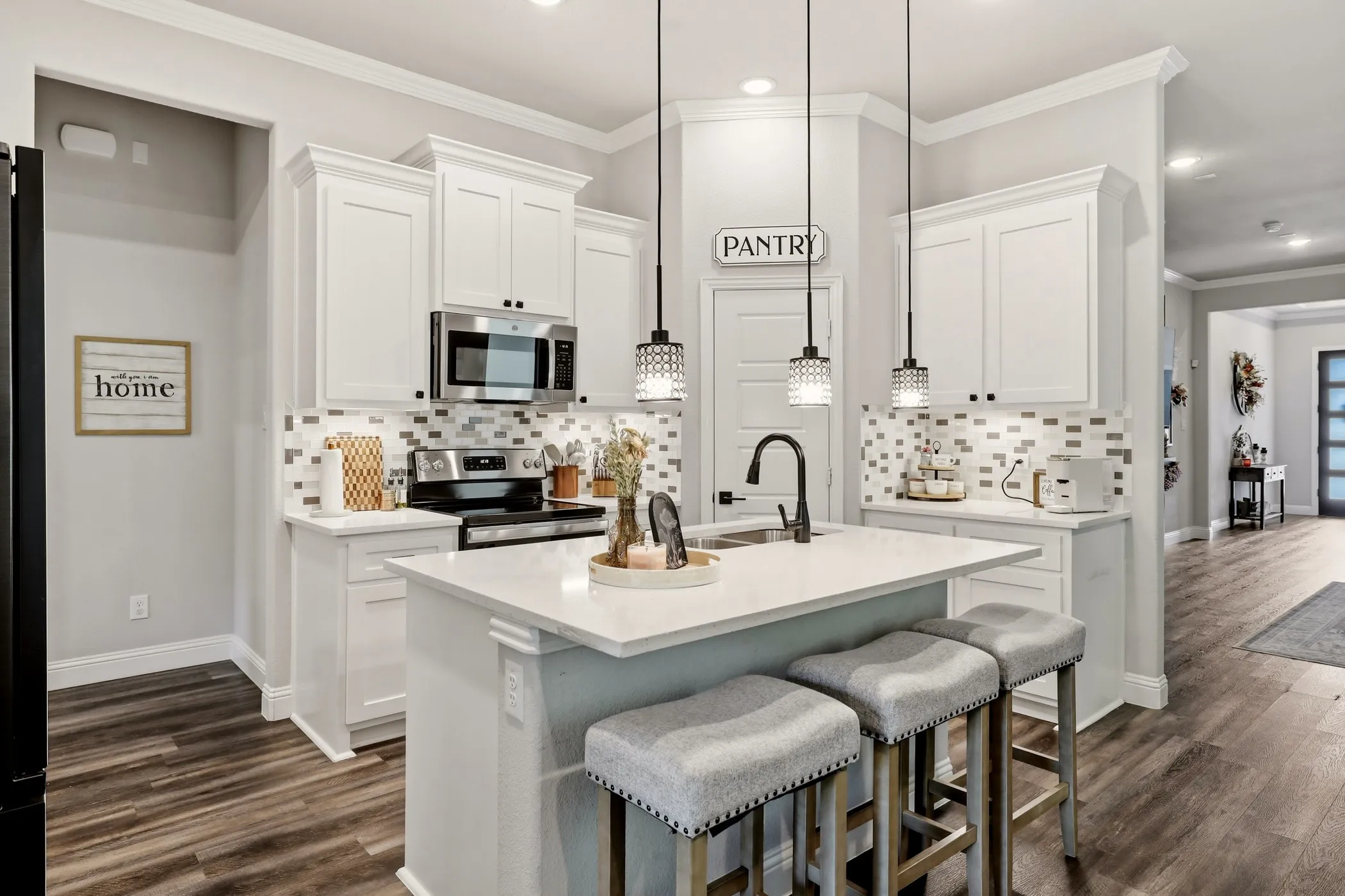 Modern kitchen featuring white cabinetry with crown molding, stainless steel appliances, and a rectangular tile backsplash