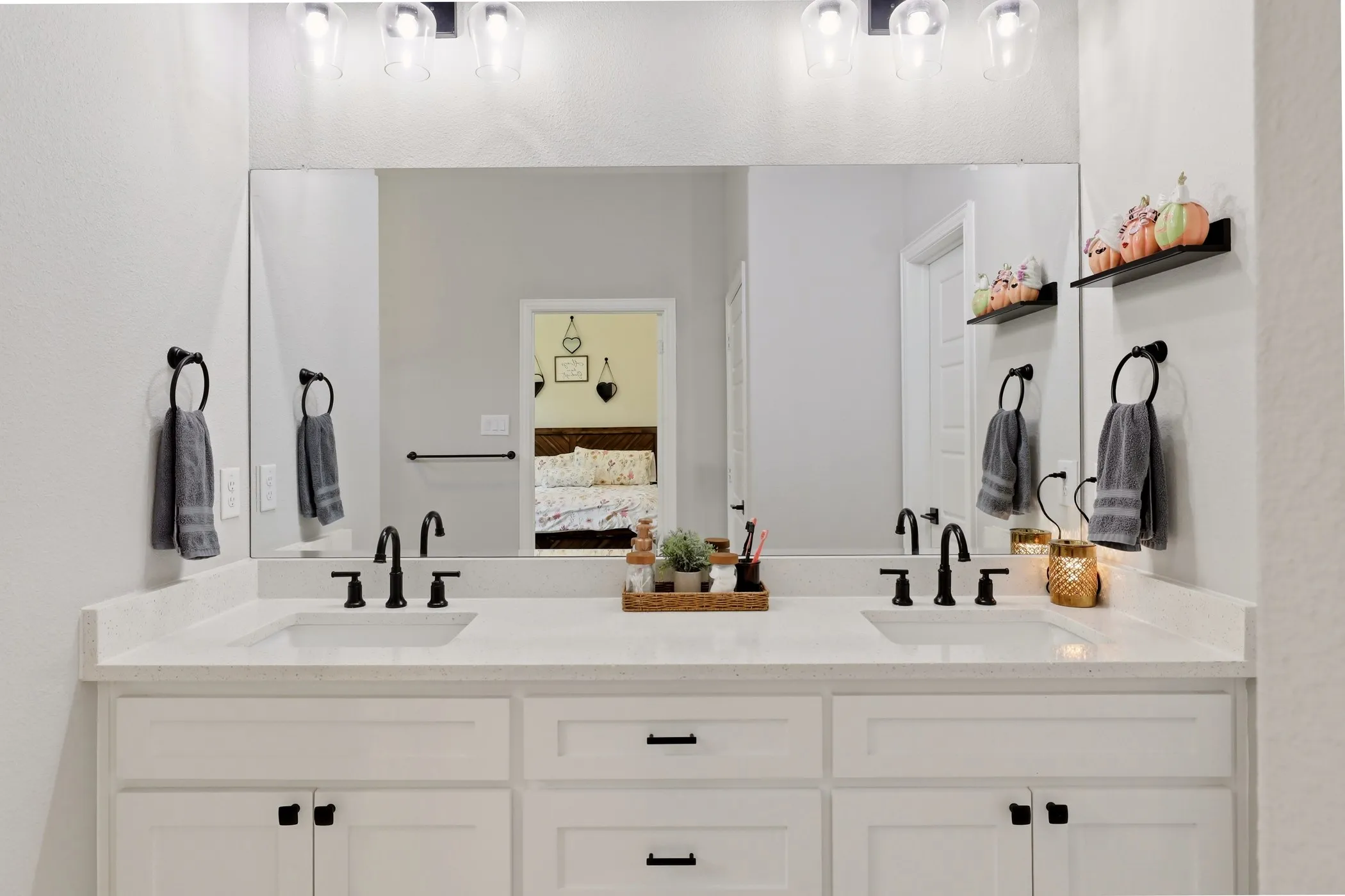 Dual-sink vanity featuring white cabinetry, light-toned countertops, and matte black plumbing fixtures