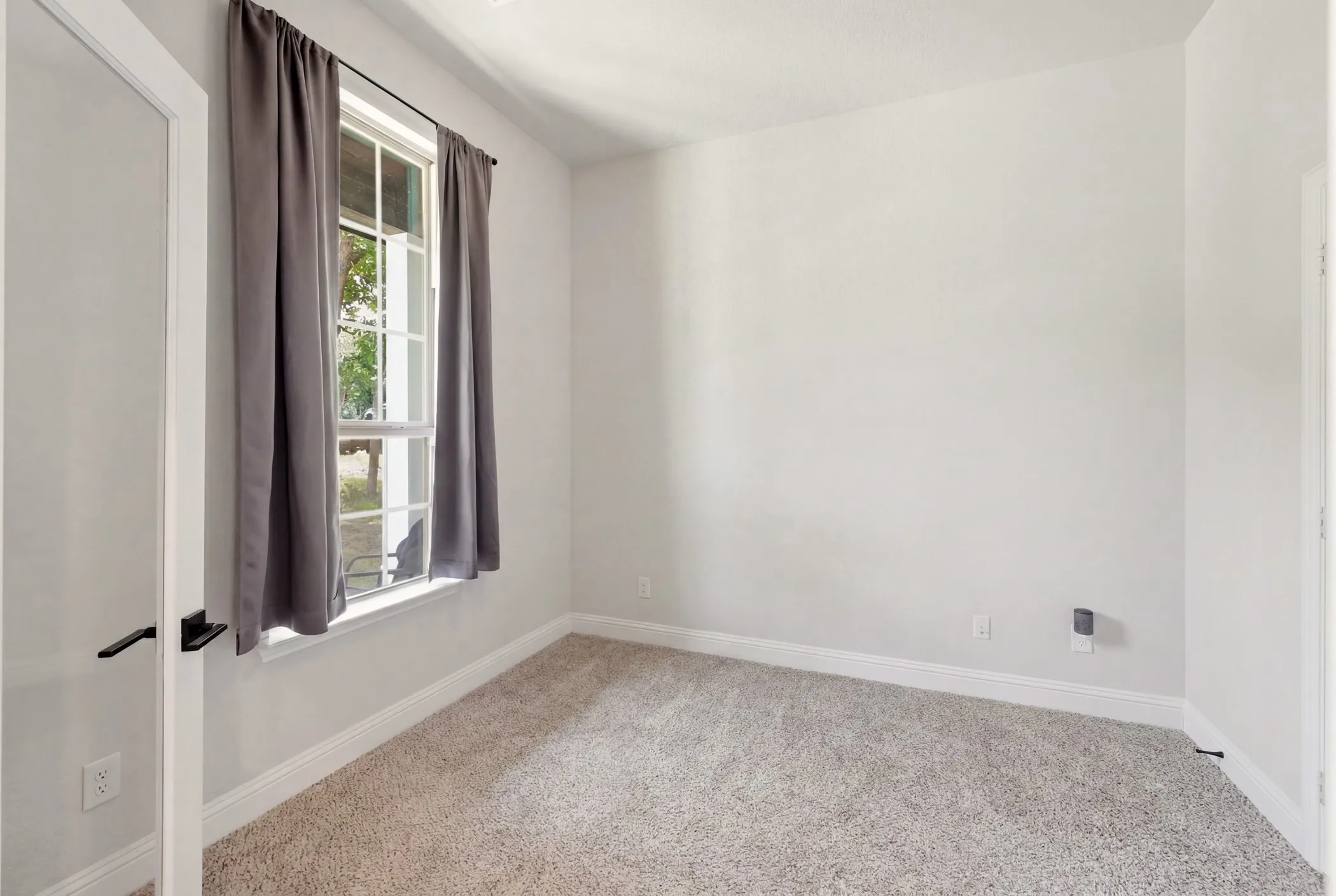 Neutral-toned room featuring light gray carpet flooring and white baseboards