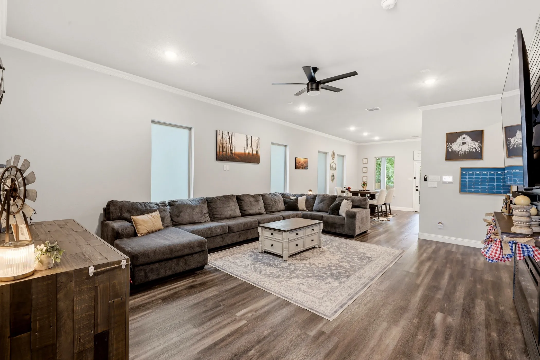 Open-concept living area featuring wood-finish flooring, recessed lighting, and crown molding
