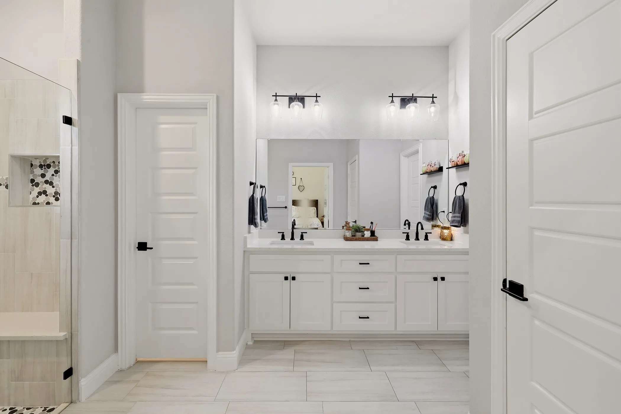 Dual sink vanity with quartz countertop, white cabinetry, and matte black fixtures