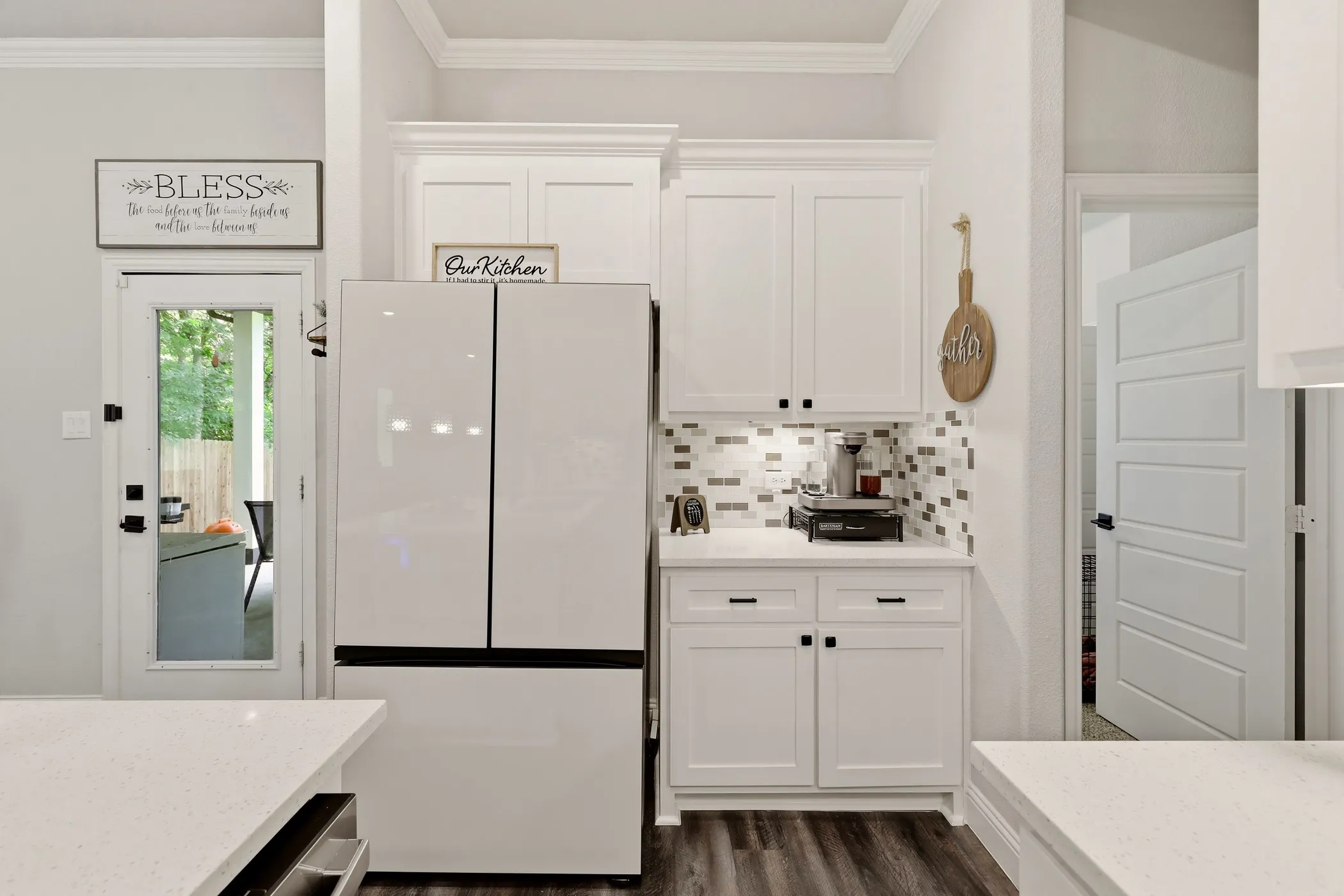 Kitchen area featuring white shaker cabinetry with dark hardware, a mosaic tile backsplash, and wood-finish flooring