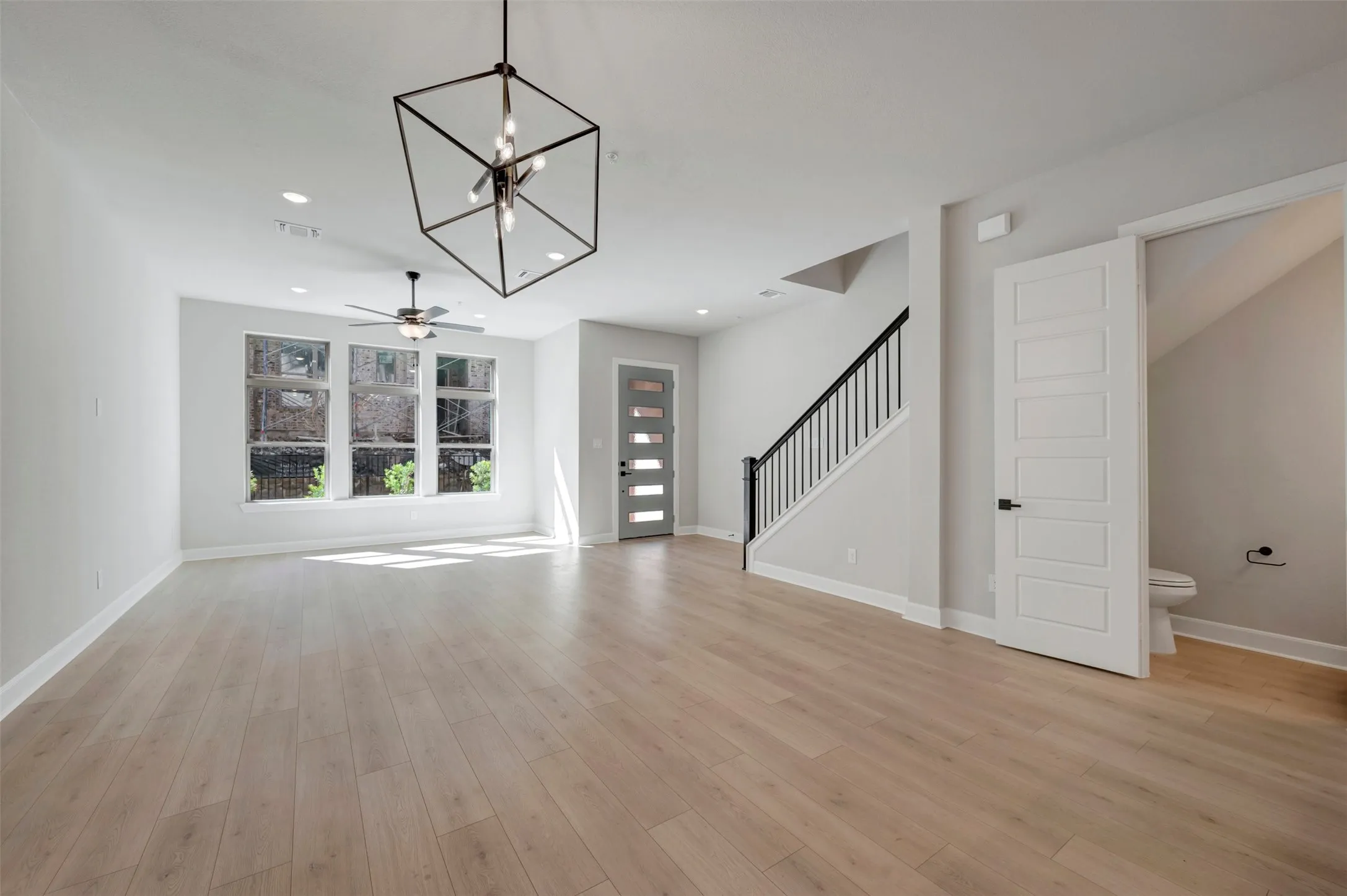 Open-concept living area featuring wood-finish flooring, recessed lighting, and a modern geometric chandelier