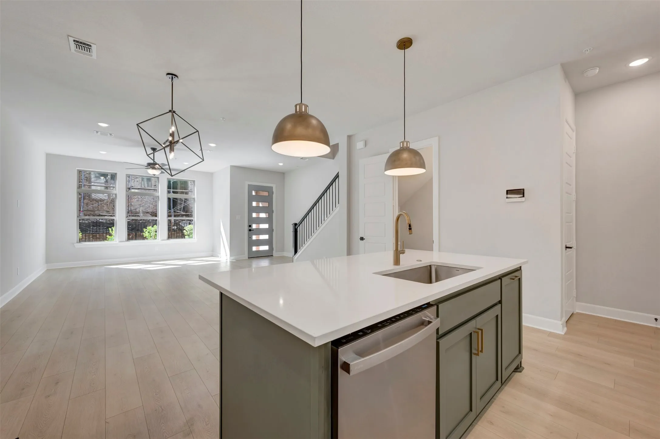 Kitchen island with white countertop, undermount sink, stainless steel dishwasher, and two pendant lights