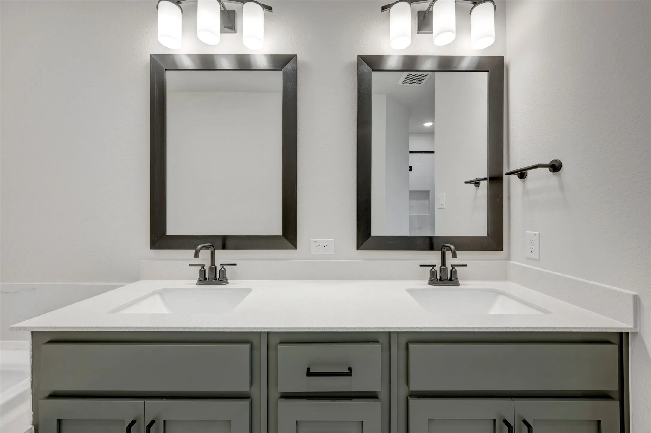 Dual vanity with undermount sinks, light-toned countertops, gray cabinetry, and matte black hardware