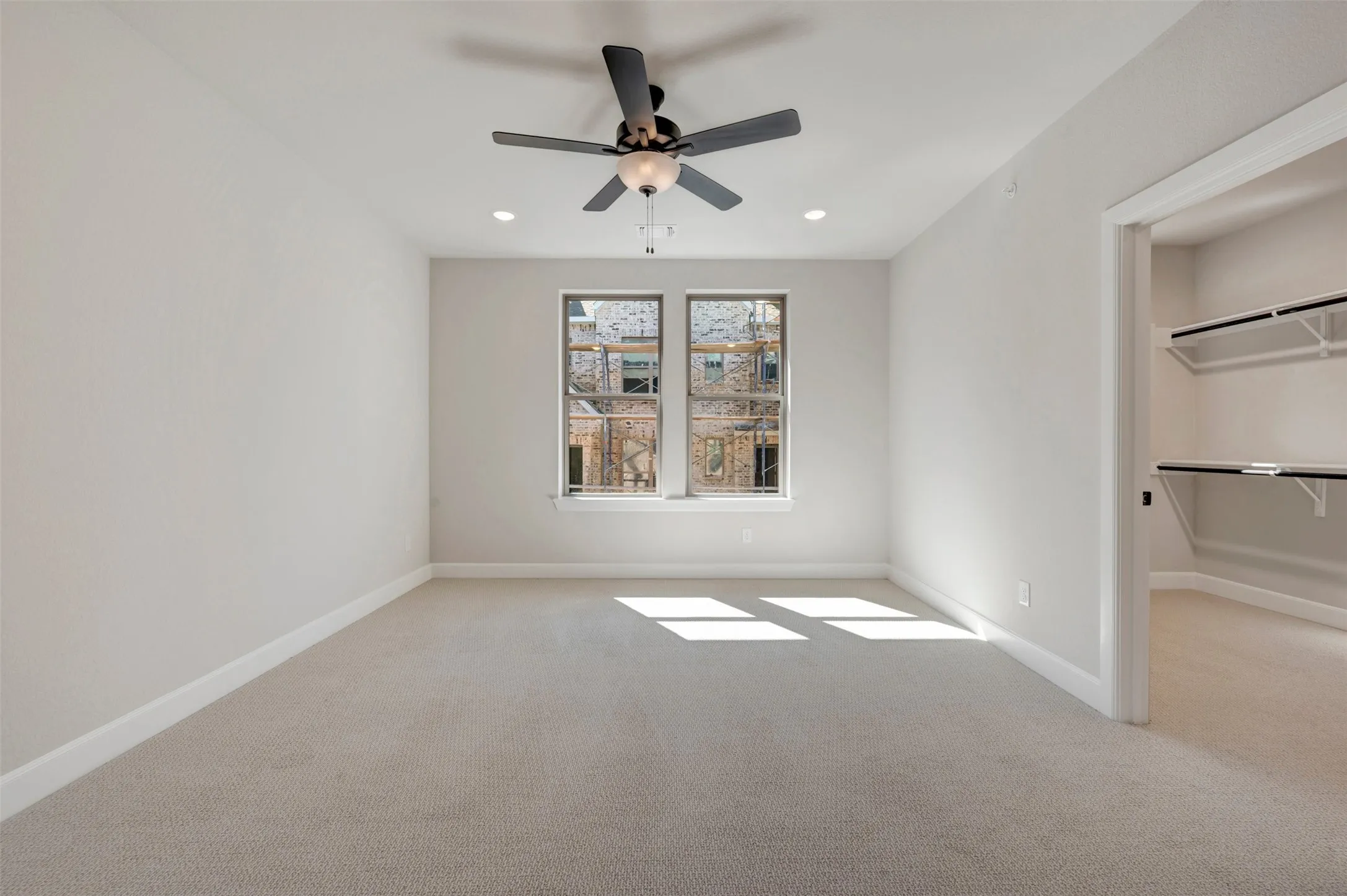 Recessed lighting, ceiling fan, carpet flooring, and a walk-in closet with built-in shelving