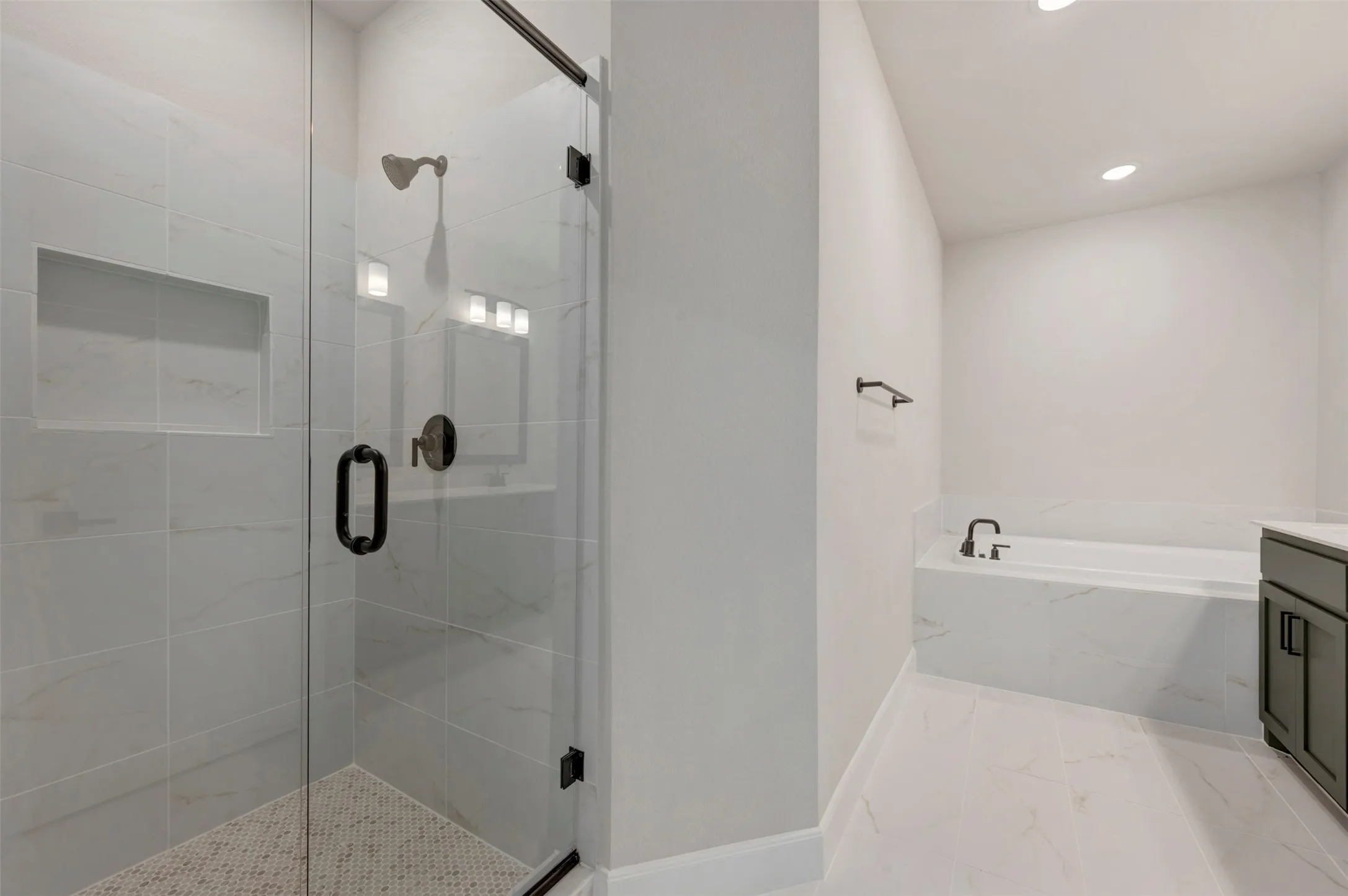 Glass-enclosed shower with a recessed shelf, hexagonal tile flooring, and matte black hardware