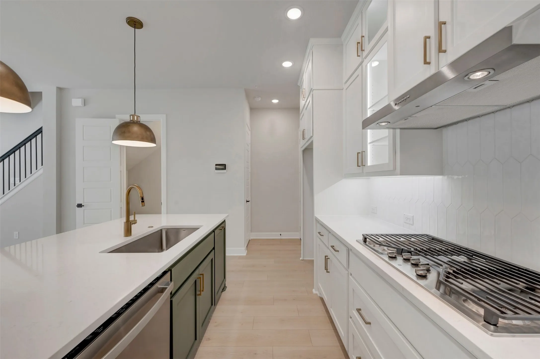Kitchen featuring a gas cooktop, stainless steel appliances, white cabinetry, a large island with a sink, and pendant lighting