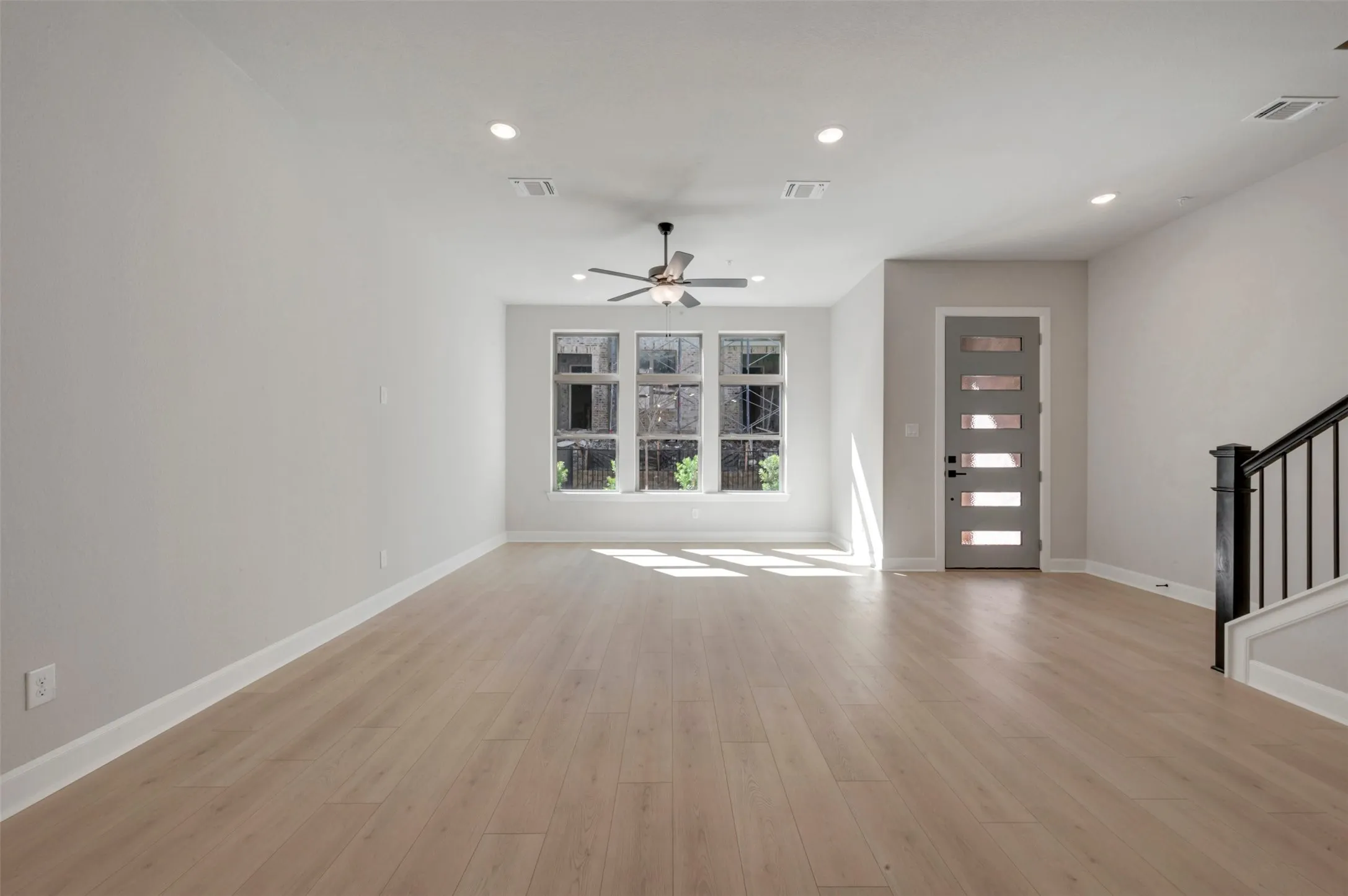 Spacious open-concept room featuring light wood-finish flooring and recessed lighting