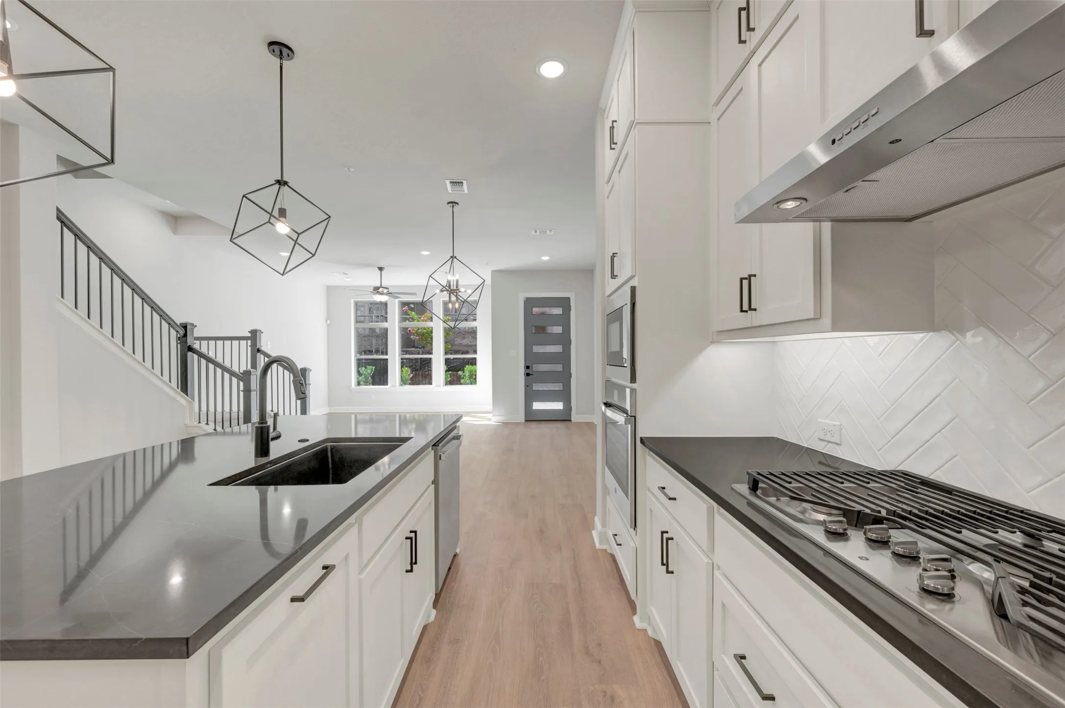 Kitchen featuring a gas range, built-in double ovens, white shaker cabinetry, and dark countertops