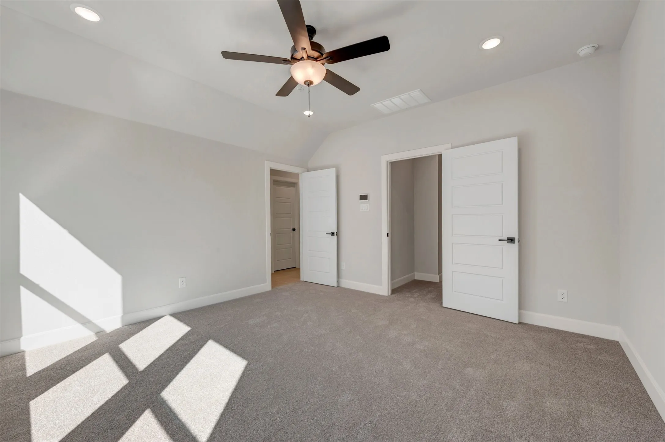 Sloped ceiling featuring recessed lighting and a ceiling fan, light gray carpeting, and paneled interior doors with black hardware