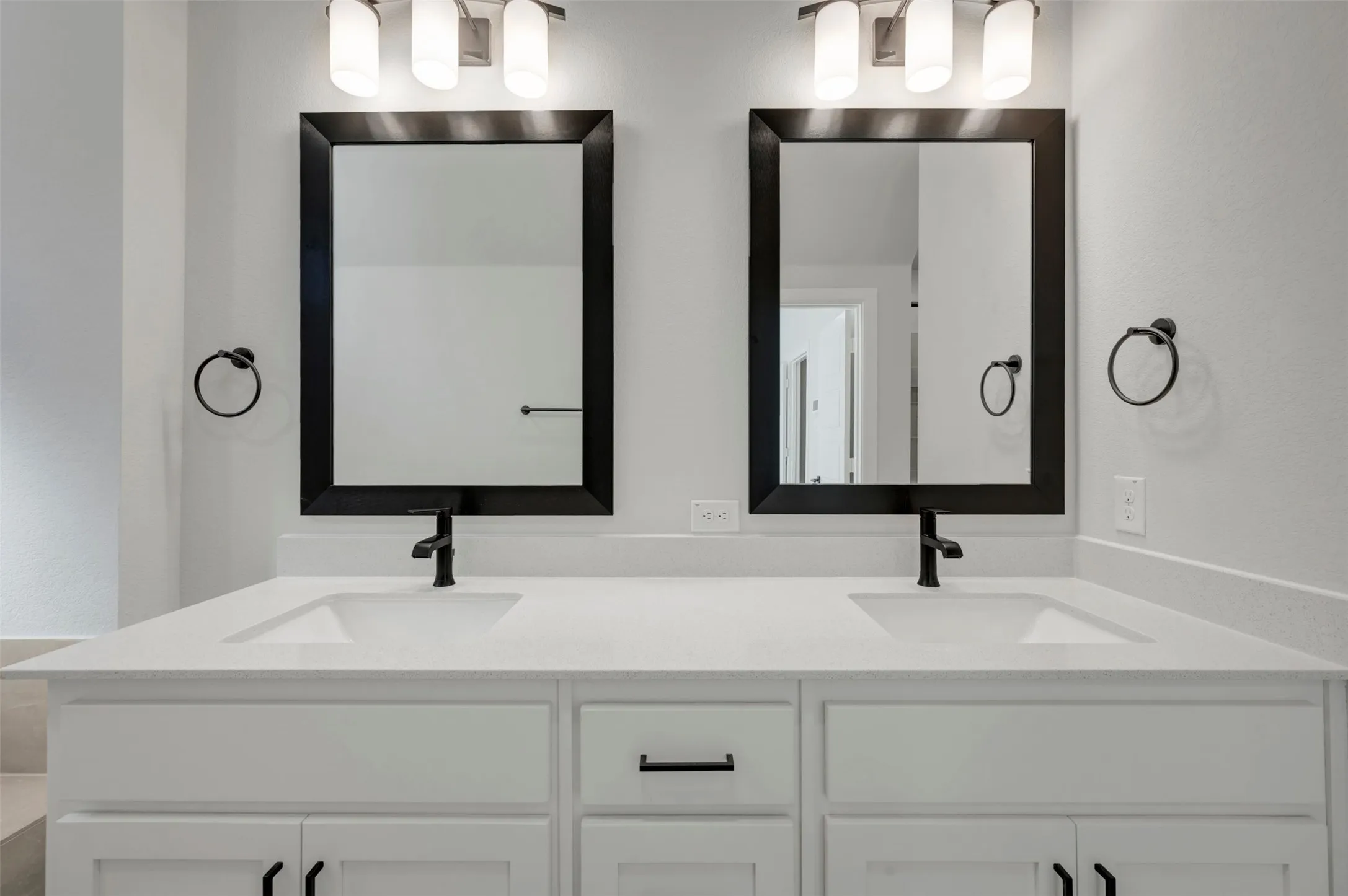 Dual vanity with integrated sinks, white cabinetry, quartz countertop, and matte black fixtures