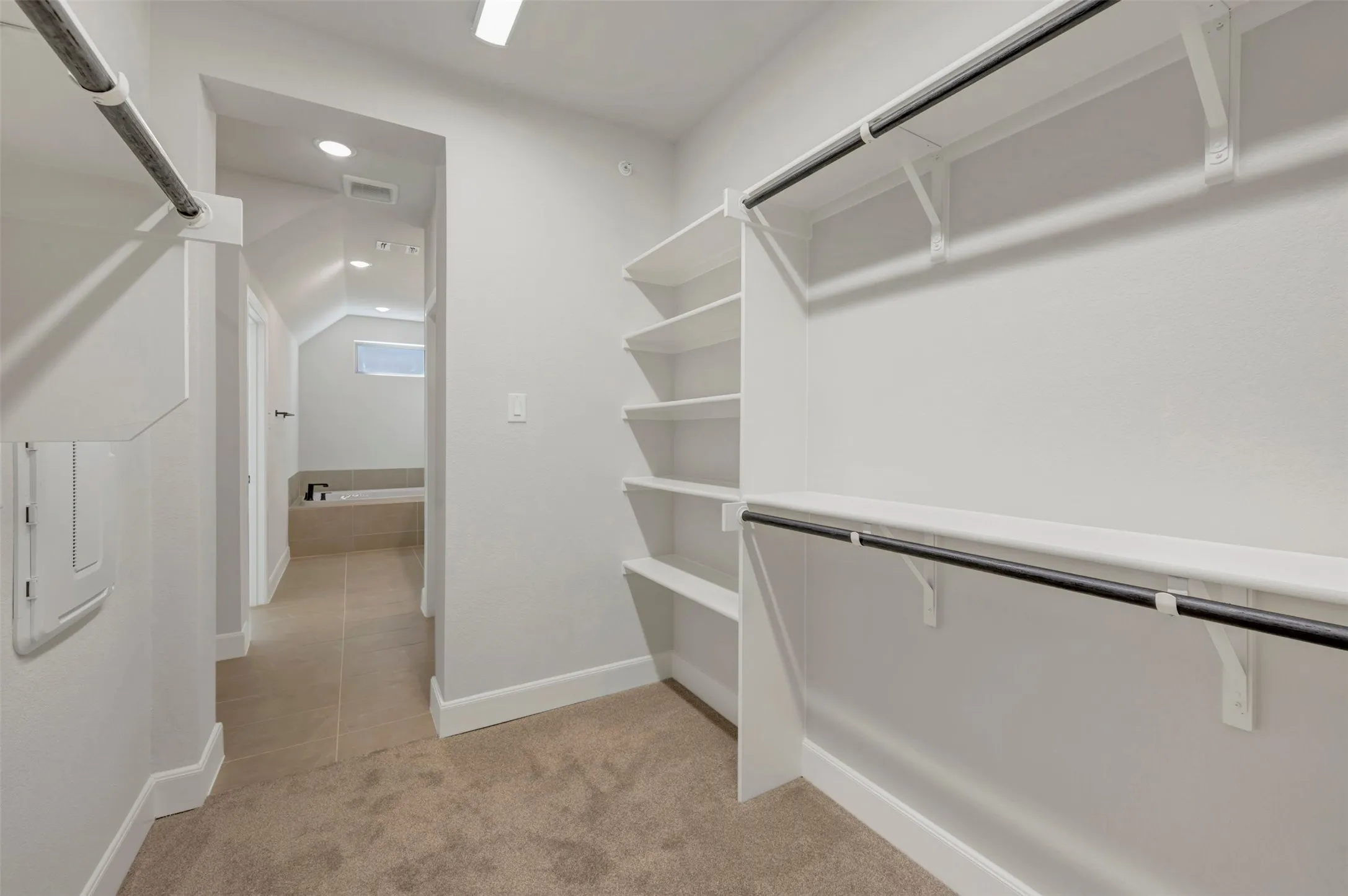 Expansive closet with built-in shelving, dual hanging rods, and soft carpet flooring