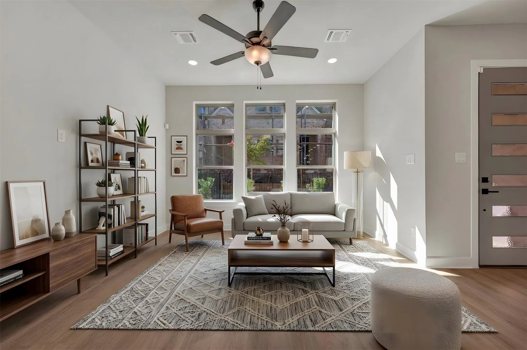 Spacious living area featuring wood-finish flooring, a contemporary ceiling fan, and recessed lighting