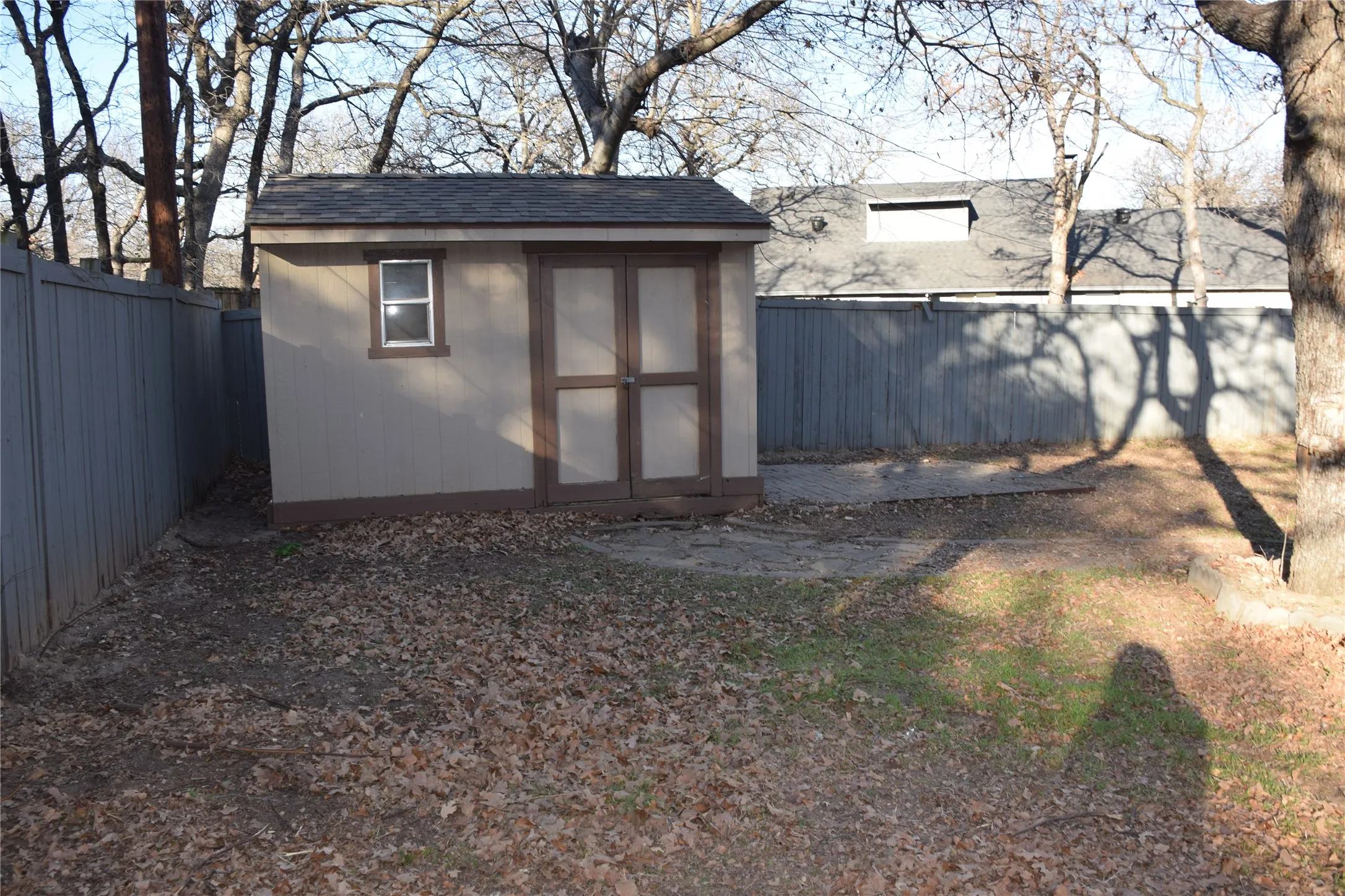 Detached storage shed featuring a shingle roof, painted siding, a single window, and double entry doors