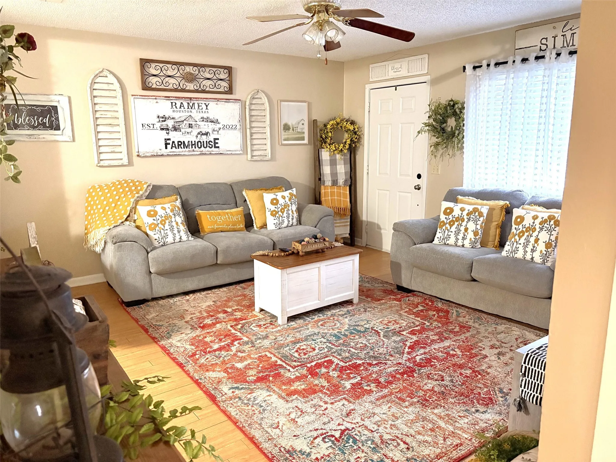 Living area featuring wood-finish flooring, a ceiling fan with integrated lighting, and a white entry door