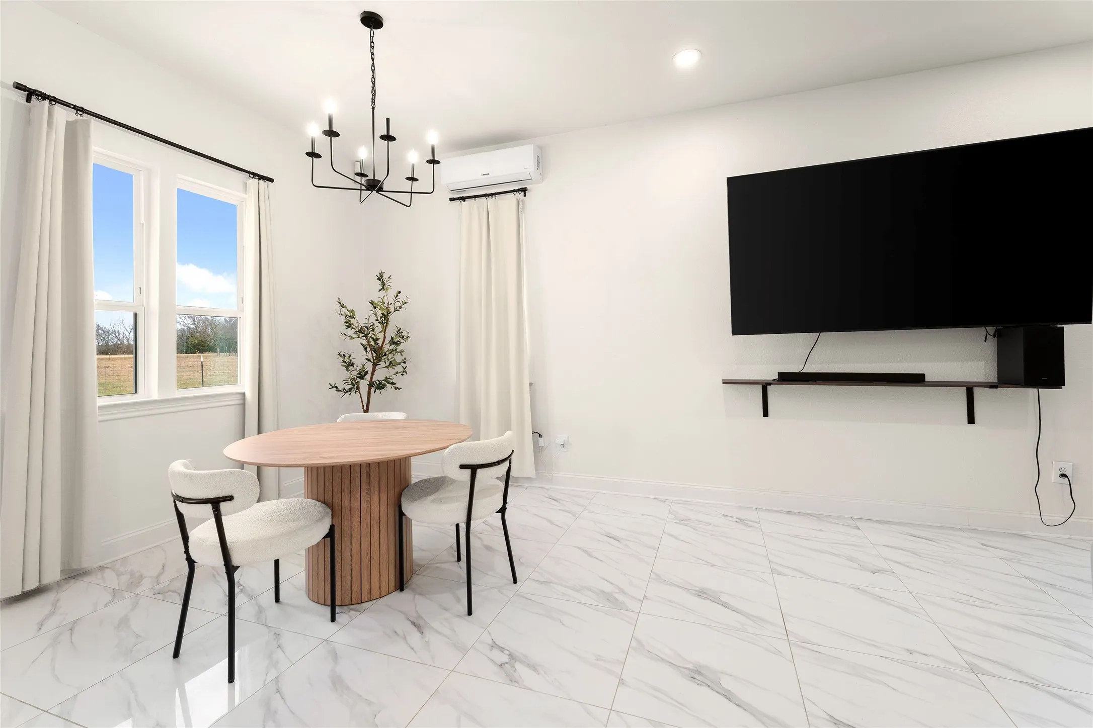 Spacious room featuring large windows, a sleek wall-mounted media shelf, and white marble-finish flooring