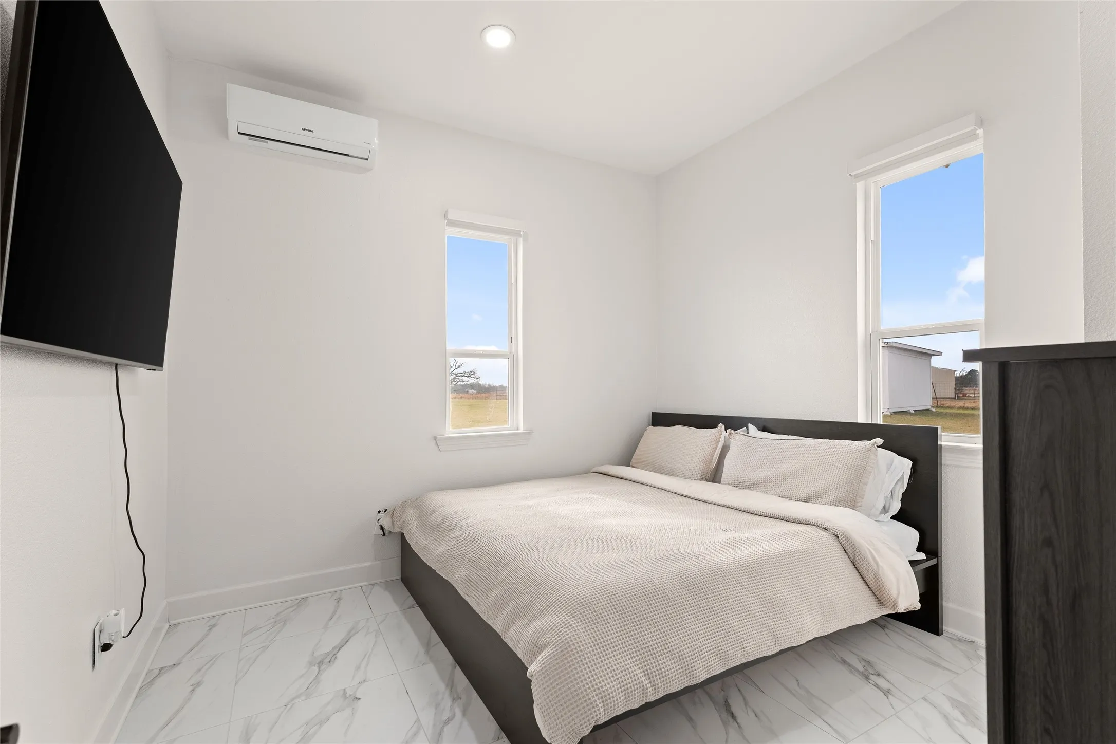 Bedroom featuring a wall-mounted mini-split system, recessed ceiling lighting, and two windows