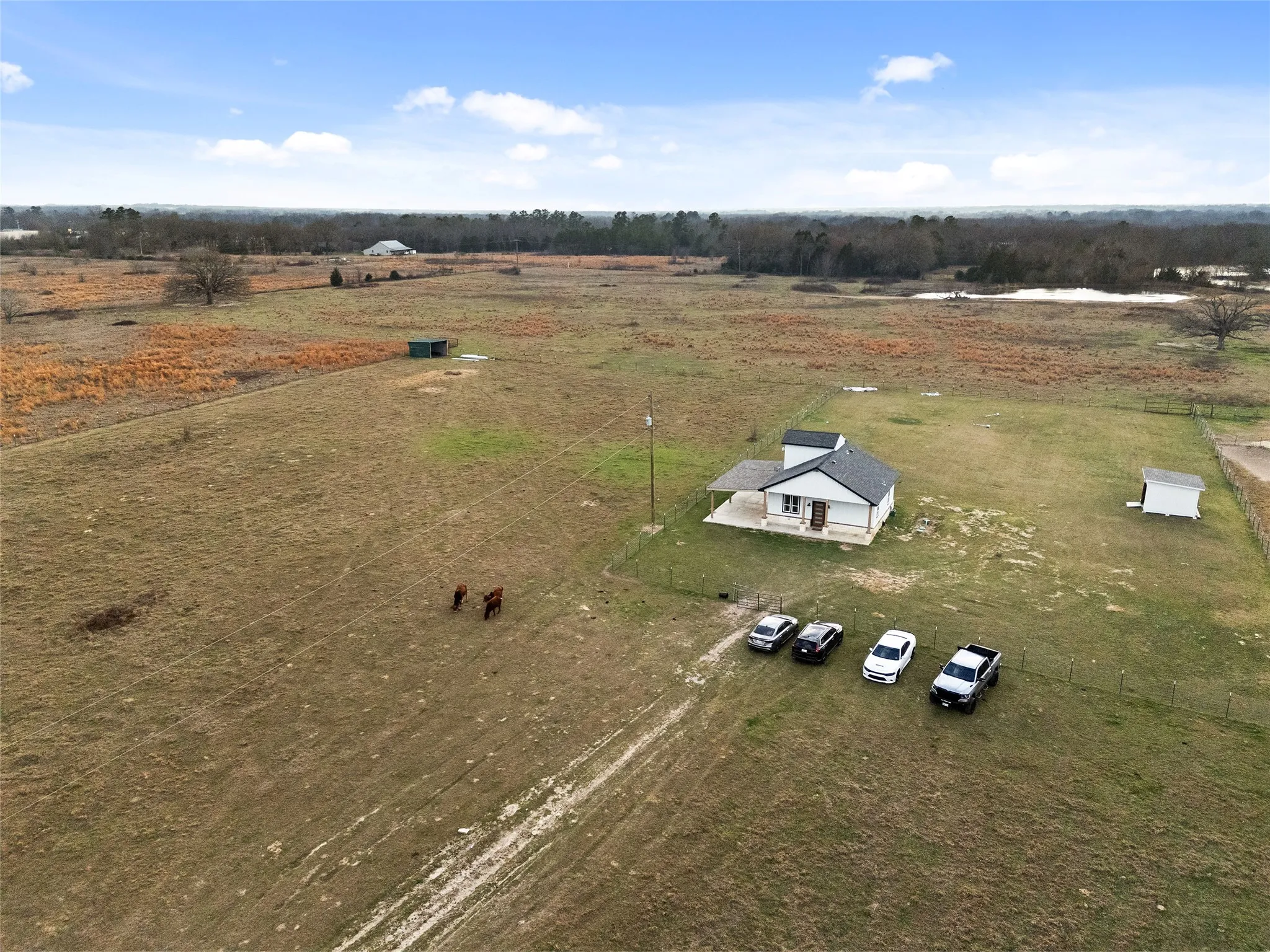 Expansive open acreage with a single-story residence featuring a covered porch