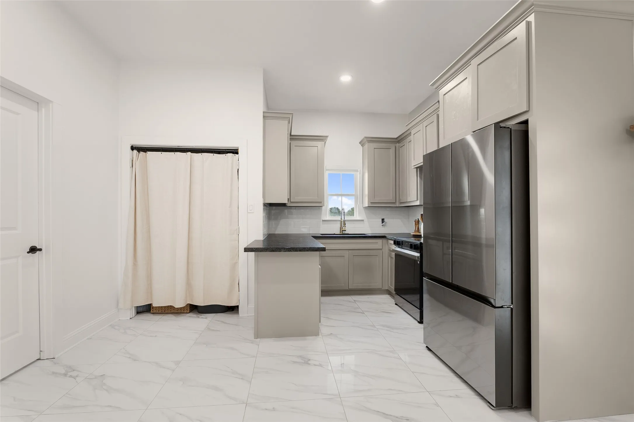 Kitchen featuring light-toned cabinetry and dark countertops