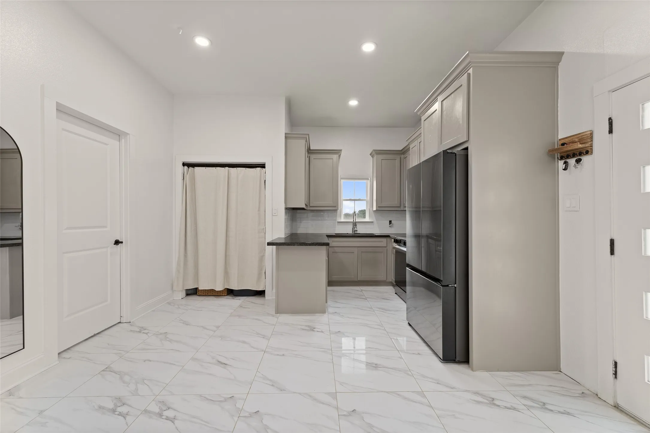 Kitchen featuring light-toned cabinetry, dark countertops, and a black stainless steel refrigerator