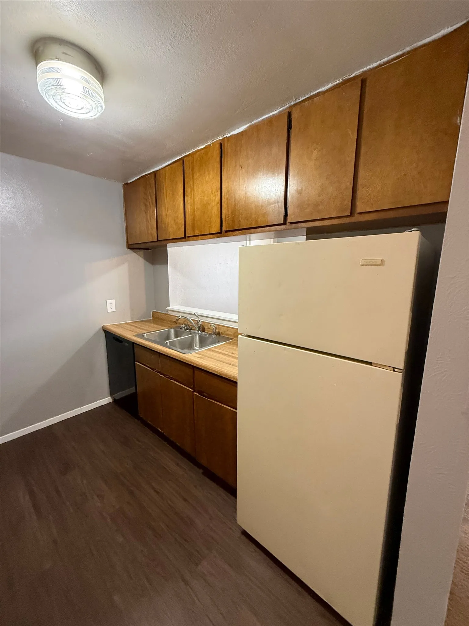 Kitchen featuring wood-finish flooring, wood cabinetry, laminate countertops, and a double basin stainless steel sink