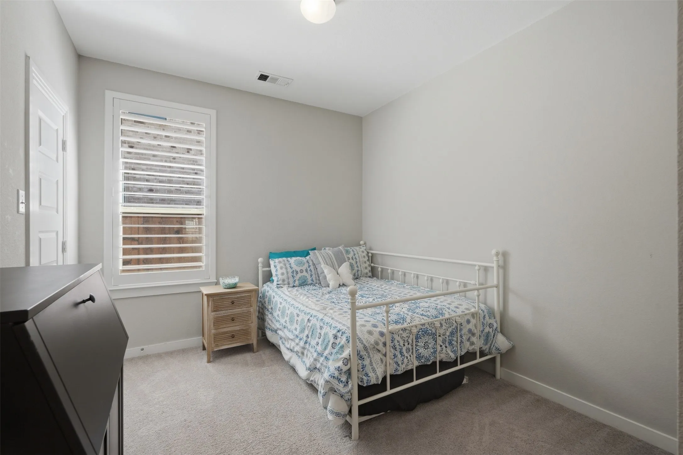 Cozy bedroom featuring soft carpet, neutral walls, plantation shutters, and plenty of natural light throughout."