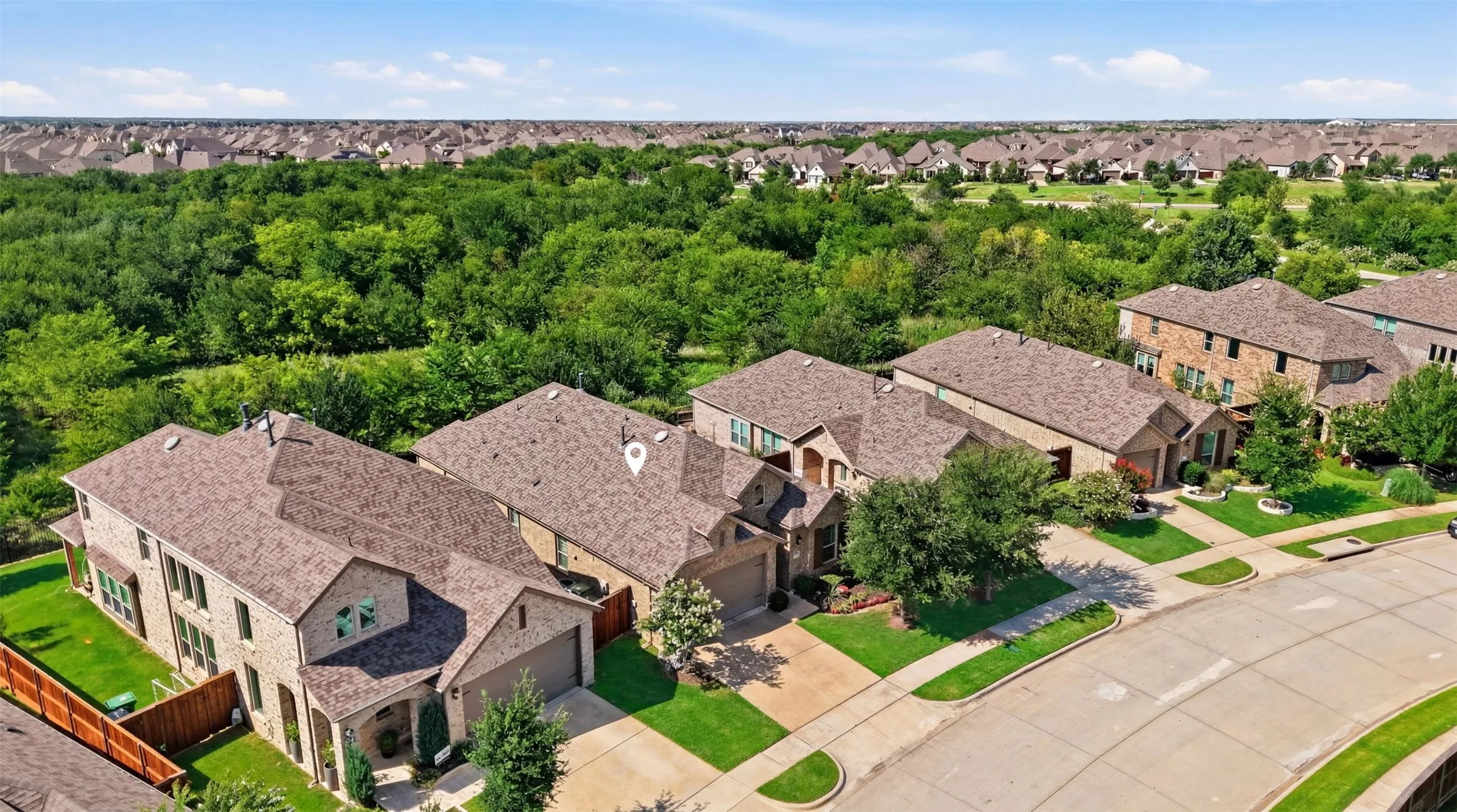 Aerial view of a single-story brick home, backing up to a lush greenbelt in a well-established neighborhood.