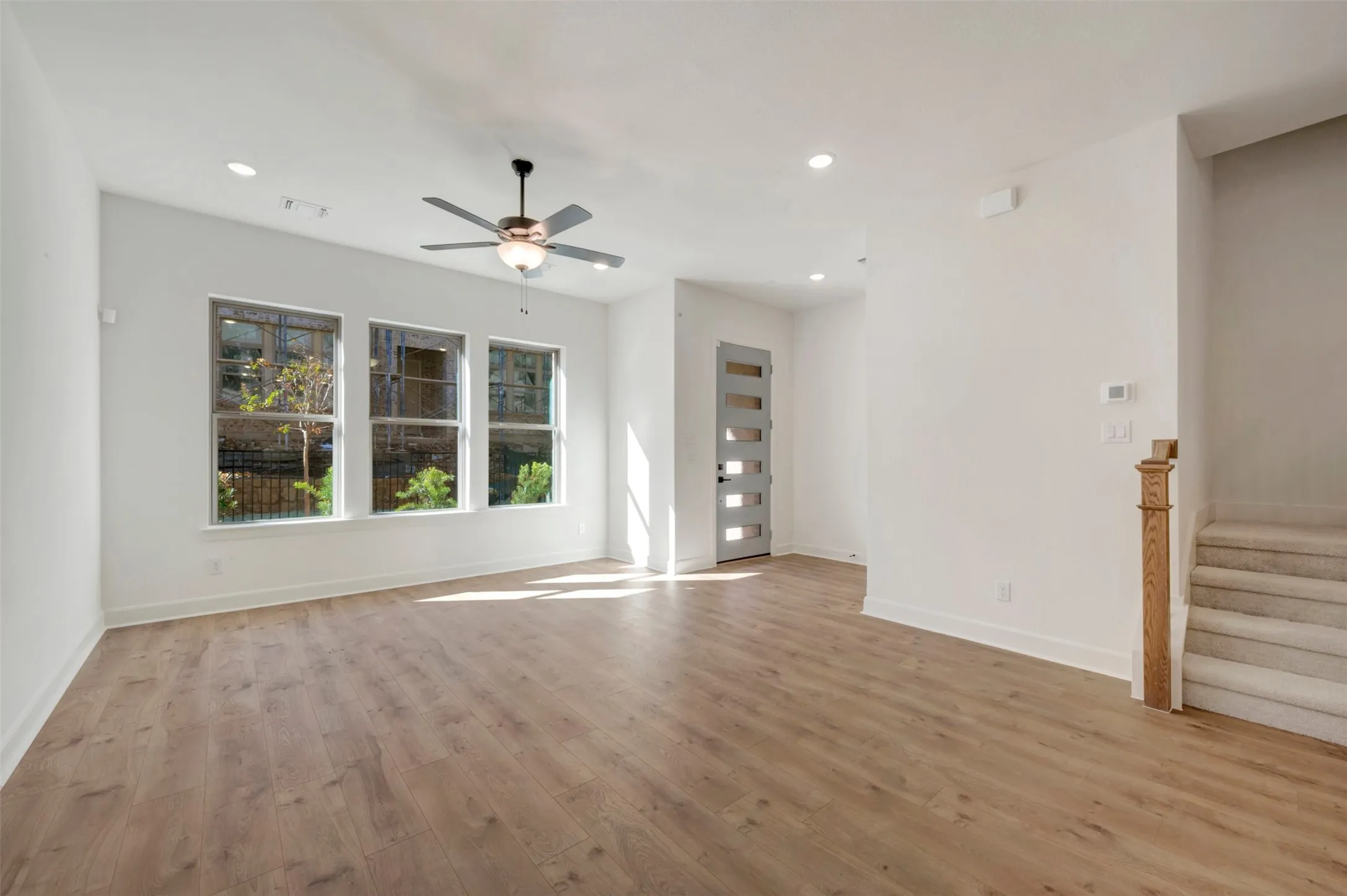 Expansive living area featuring wood-finish flooring, recessed lighting, and a contemporary ceiling fan