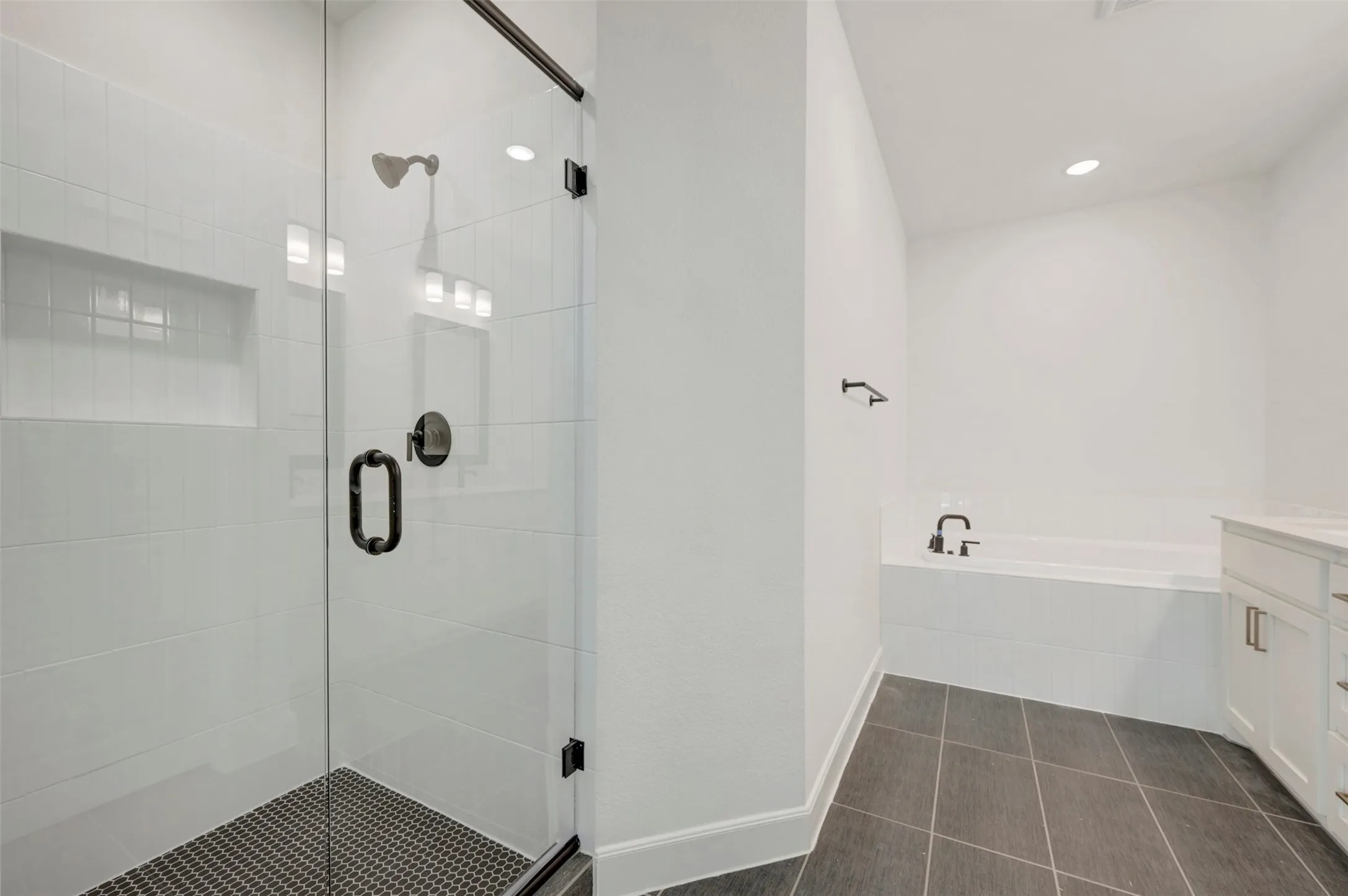 Glass-enclosed shower with dark hardware, white subway tile surround, and built-in niche