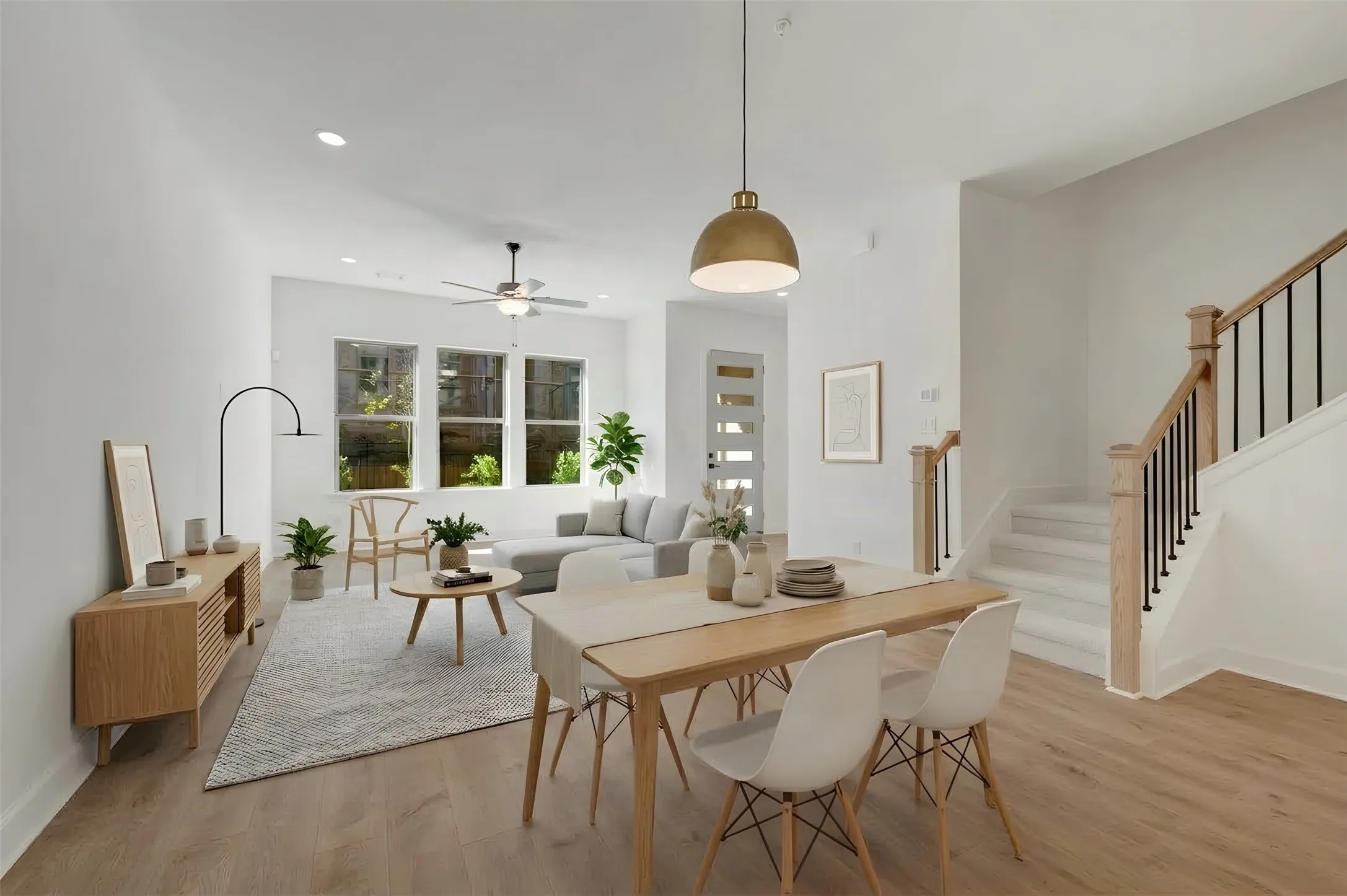 Open-concept living and dining area featuring wood-finish flooring, recessed lighting, a modern ceiling fan, and a wood staircase with black iron balusters