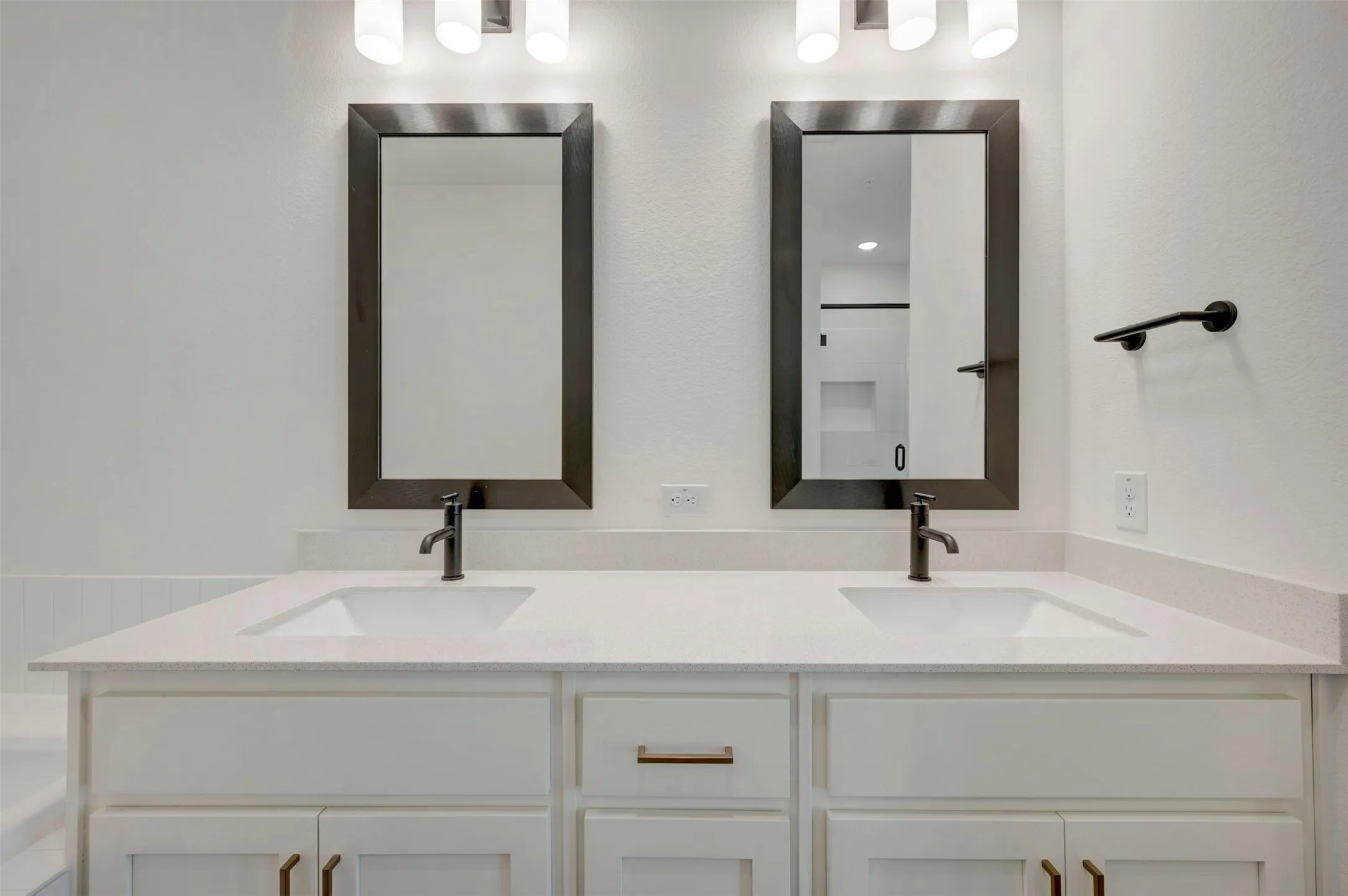 Dual vanity with white cabinetry, integrated sinks, white countertops, and matte black fixtures