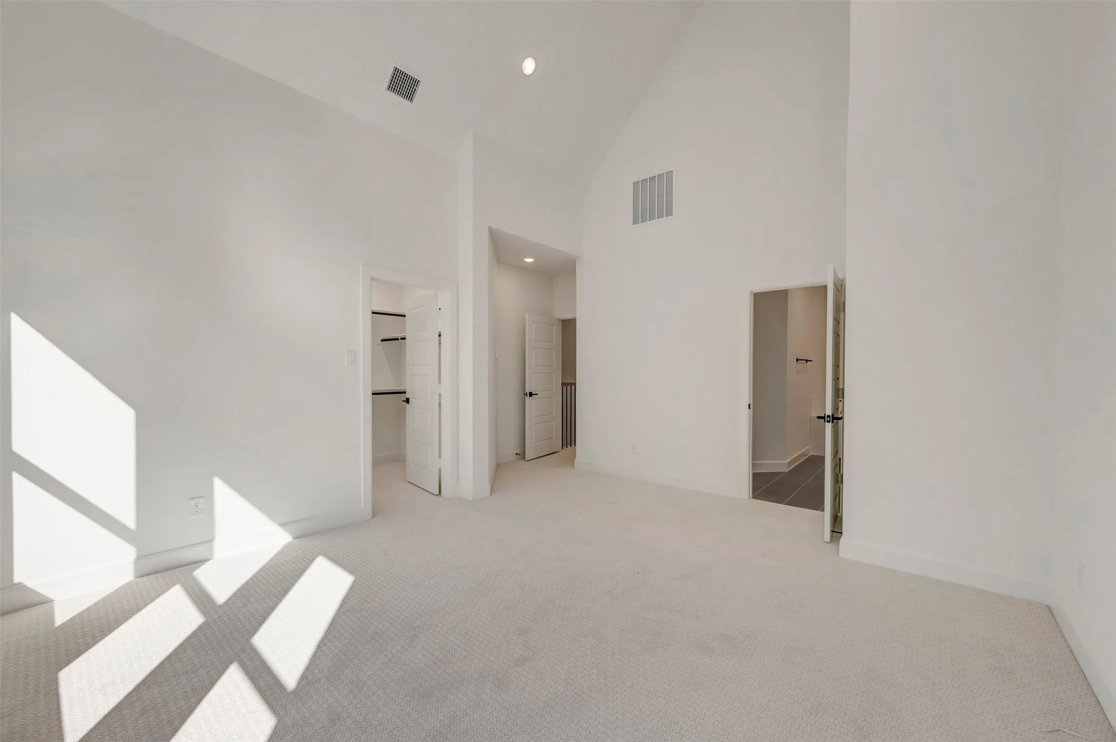 Vaulted ceiling with recessed lighting, carpet flooring, and white walls