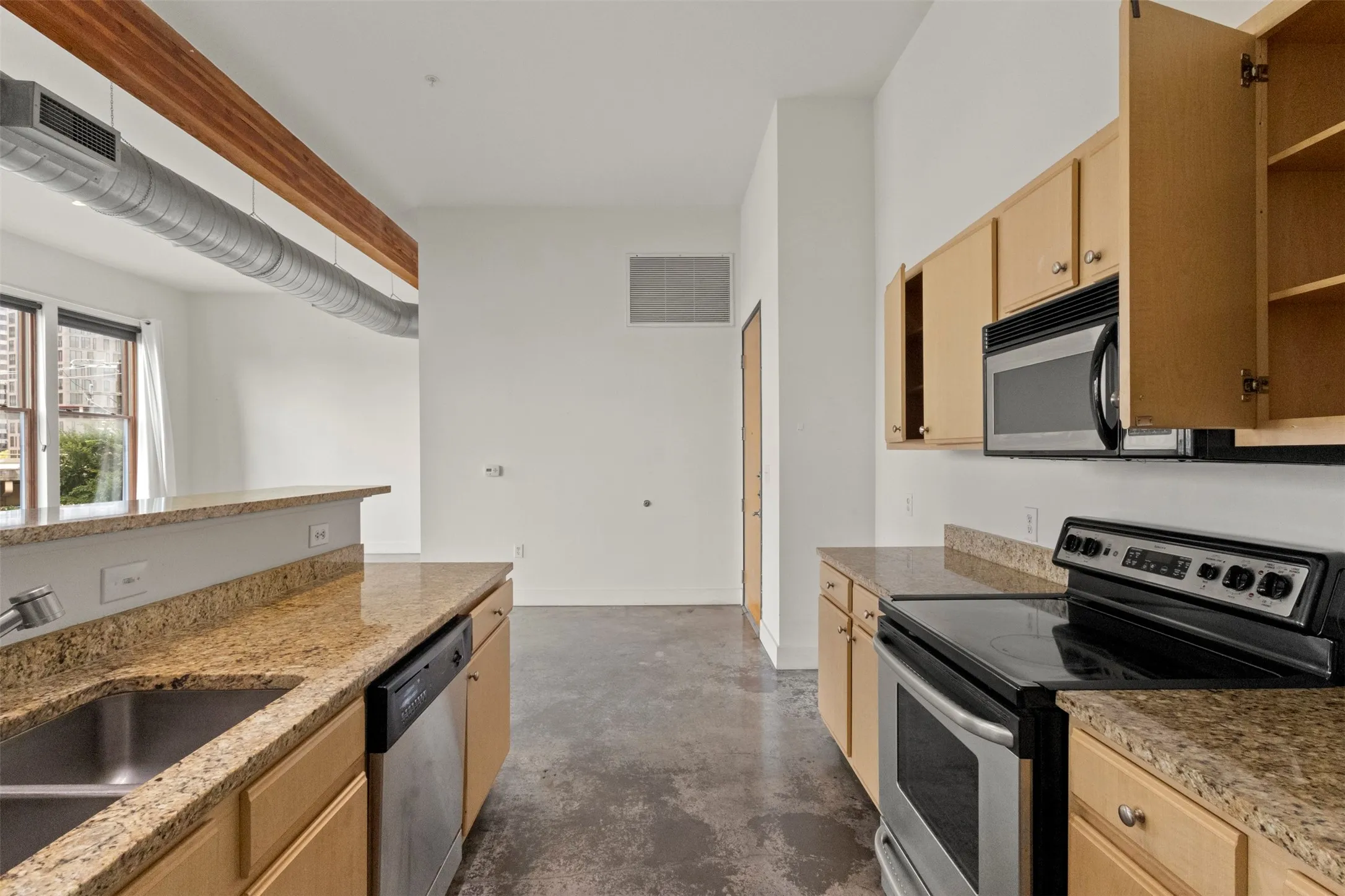 Kitchen featuring granite countertops, stainless steel appliances, light wood cabinetry, and exposed ductwork