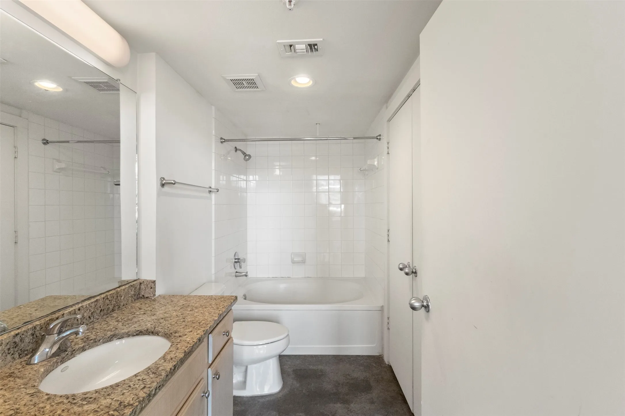 Bathroom featuring a single vanity with stone-finish countertop, under-mount sink, and chrome faucet