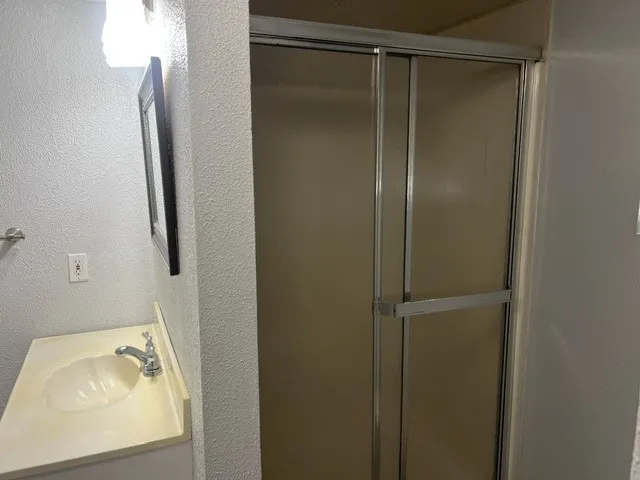Shower enclosure with sliding frosted panels and chrome framing