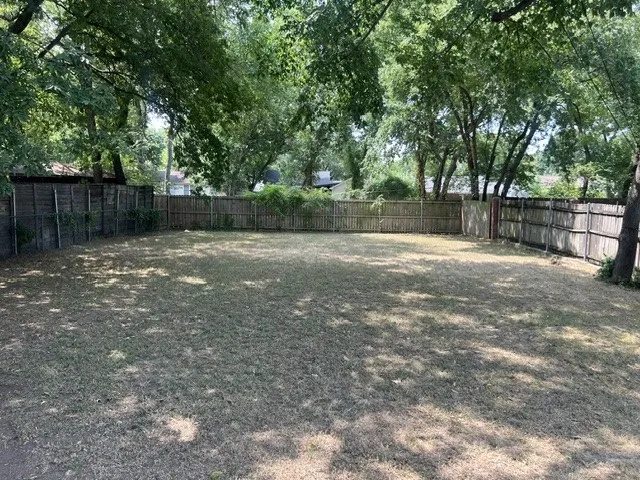 Spacious backyard with mature tree canopy and wood fencing