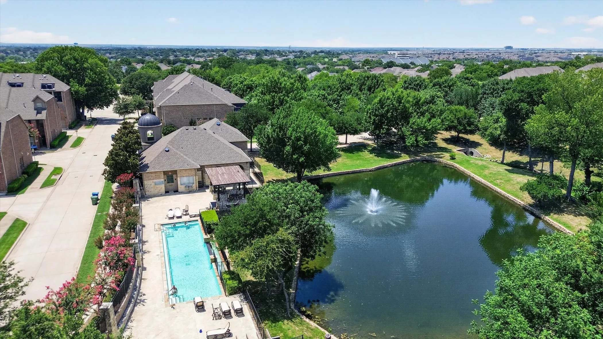 Community pond with fountain feature, surrounded by mature trees and green spaces