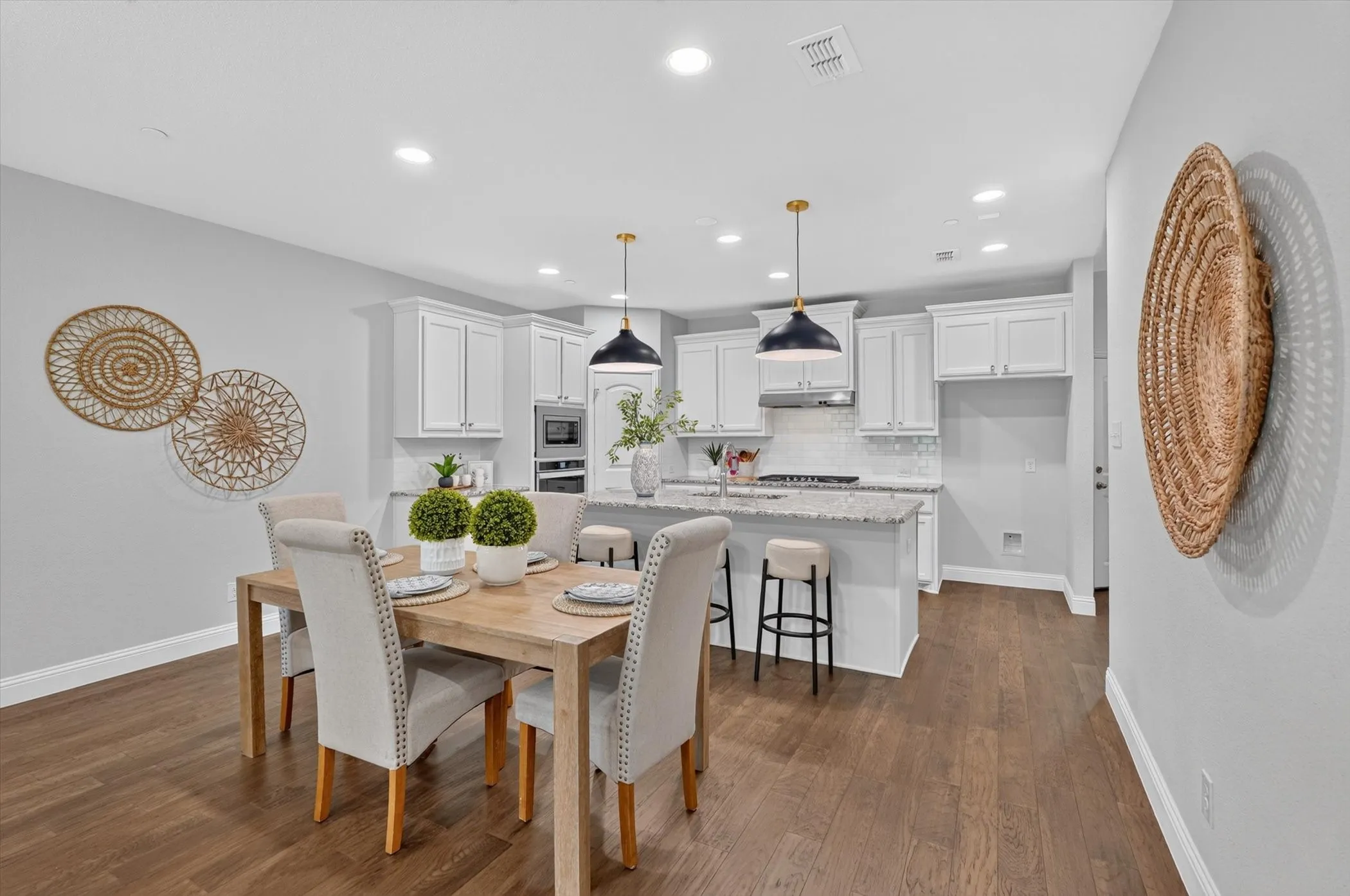 Open-concept dining area and kitchen featuring wood-finish flooring, recessed lighting, white shaker cabinetry, and a kitchen island with seating
