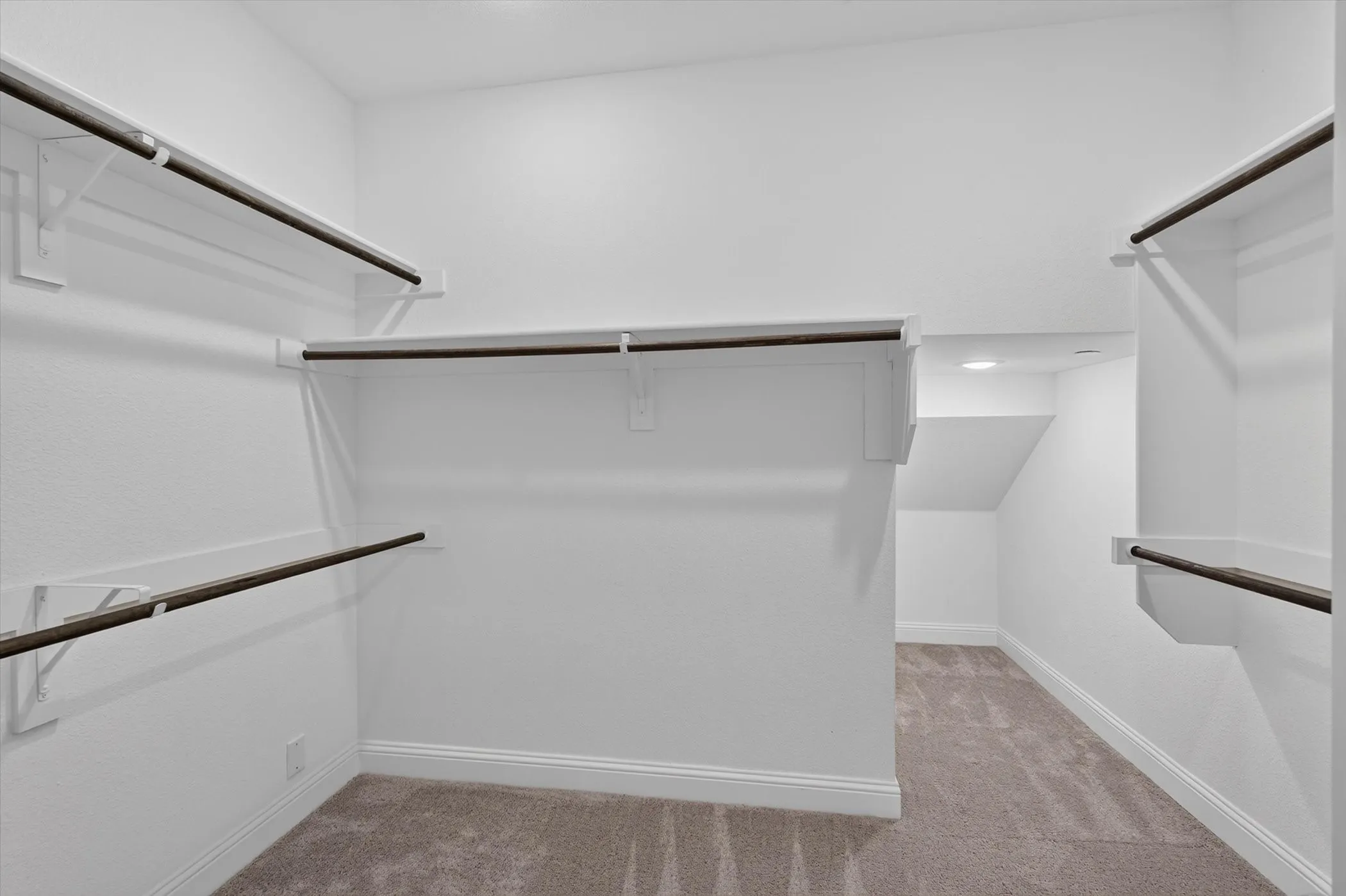 Spacious walk-in closet featuring multiple shelving units and hanging rods