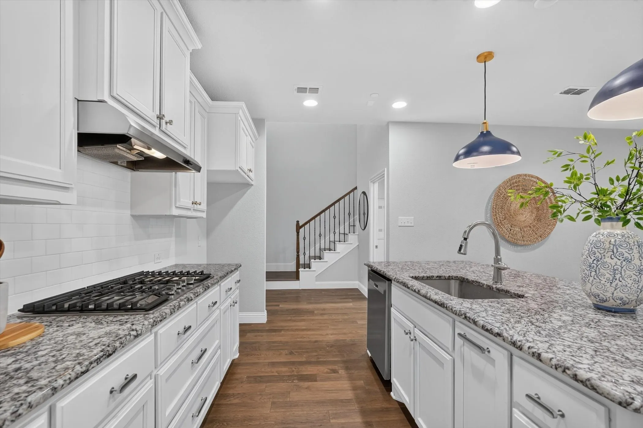 Kitchen featuring white shaker-style cabinetry, granite countertops, subway tile backsplash, and a gas range with an overhead exhaust fan
