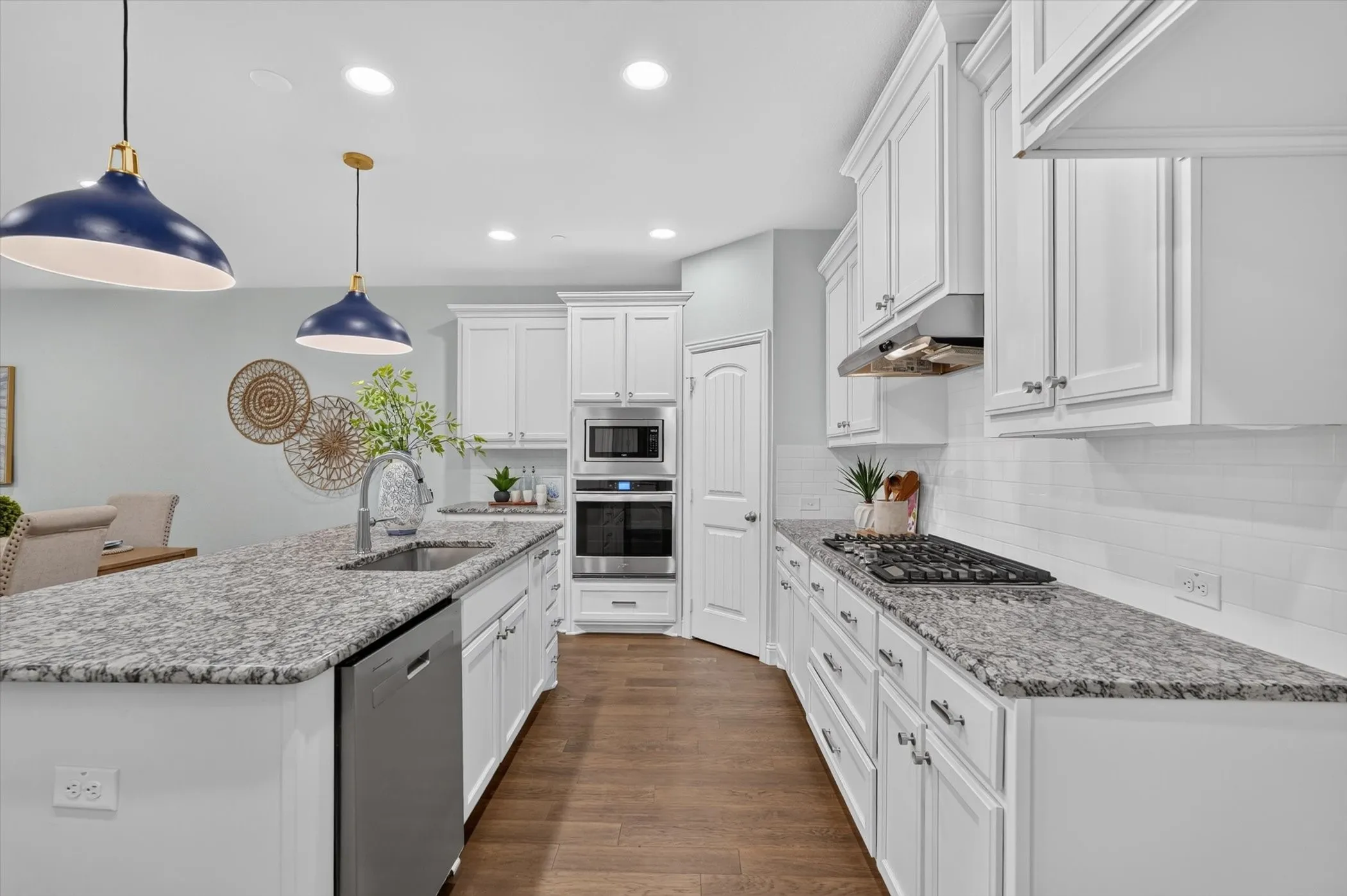 Kitchen featuring white cabinetry, granite countertops, stainless steel appliances, a gas cooktop, and wood-finish flooring