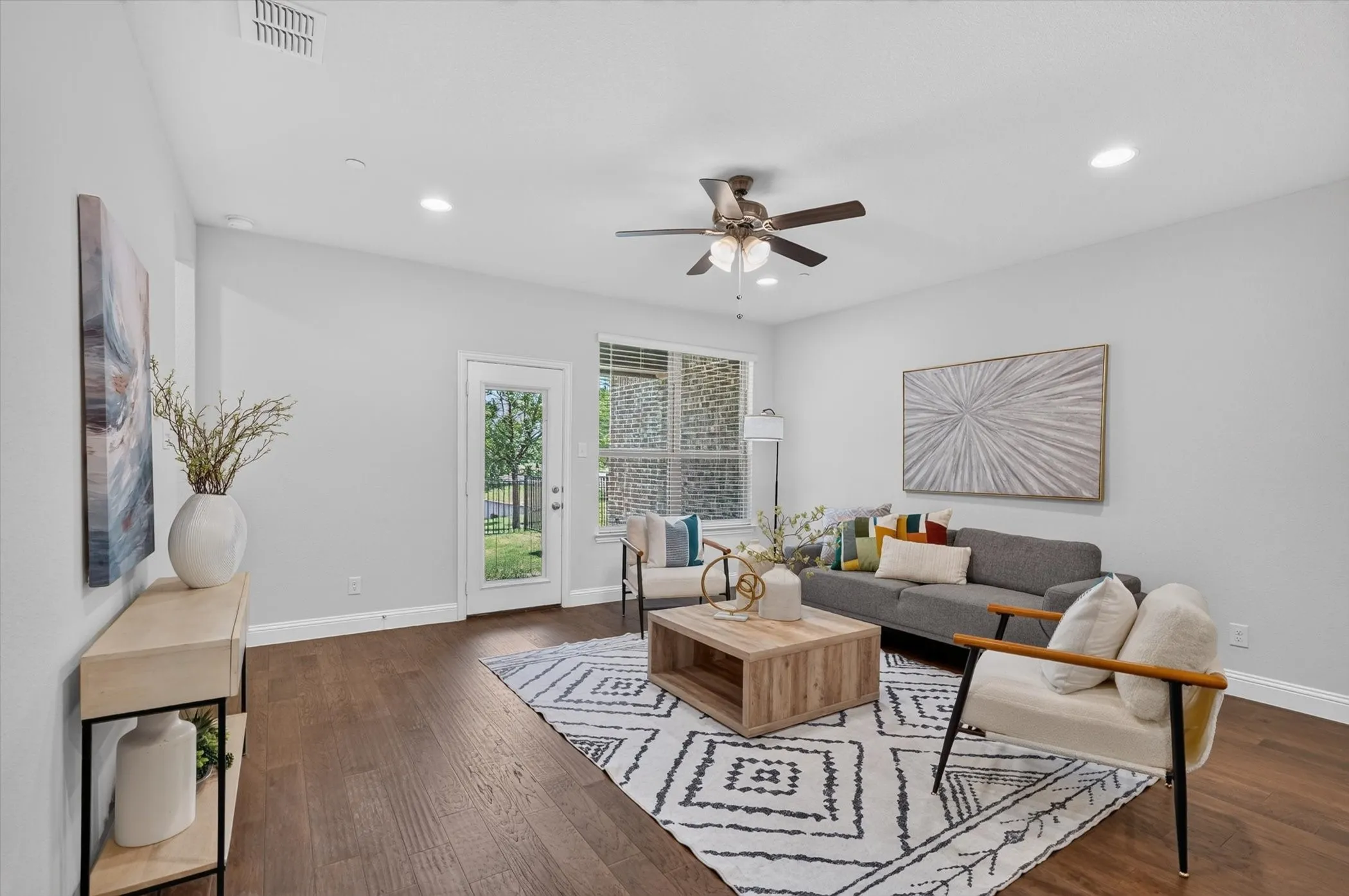 Spacious living area featuring wood-finish flooring, recessed lighting, and a ceiling fan with light kit