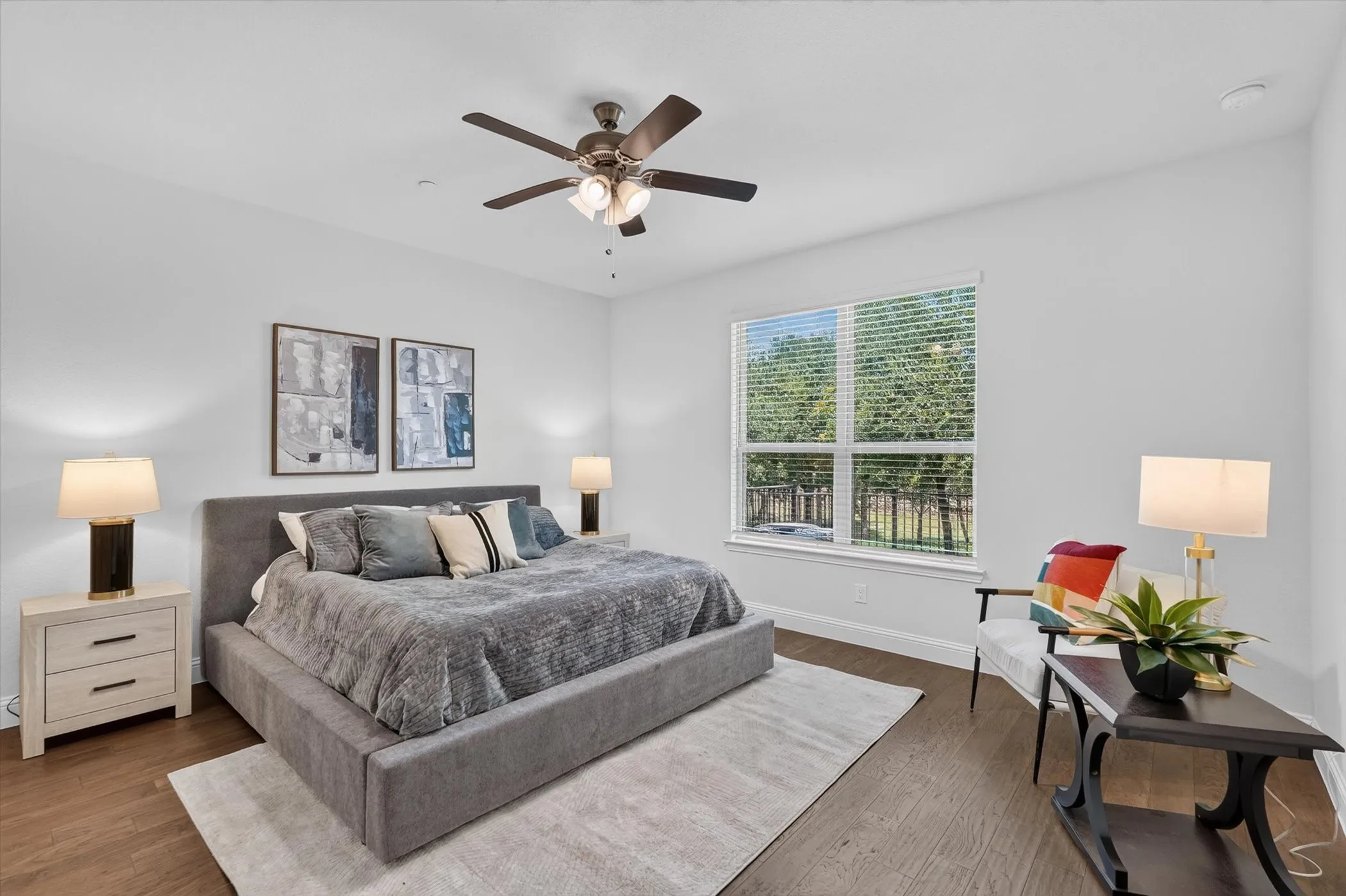 Spacious room featuring wood-finish flooring, a ceiling fan with integrated lighting, and a large window with blinds
