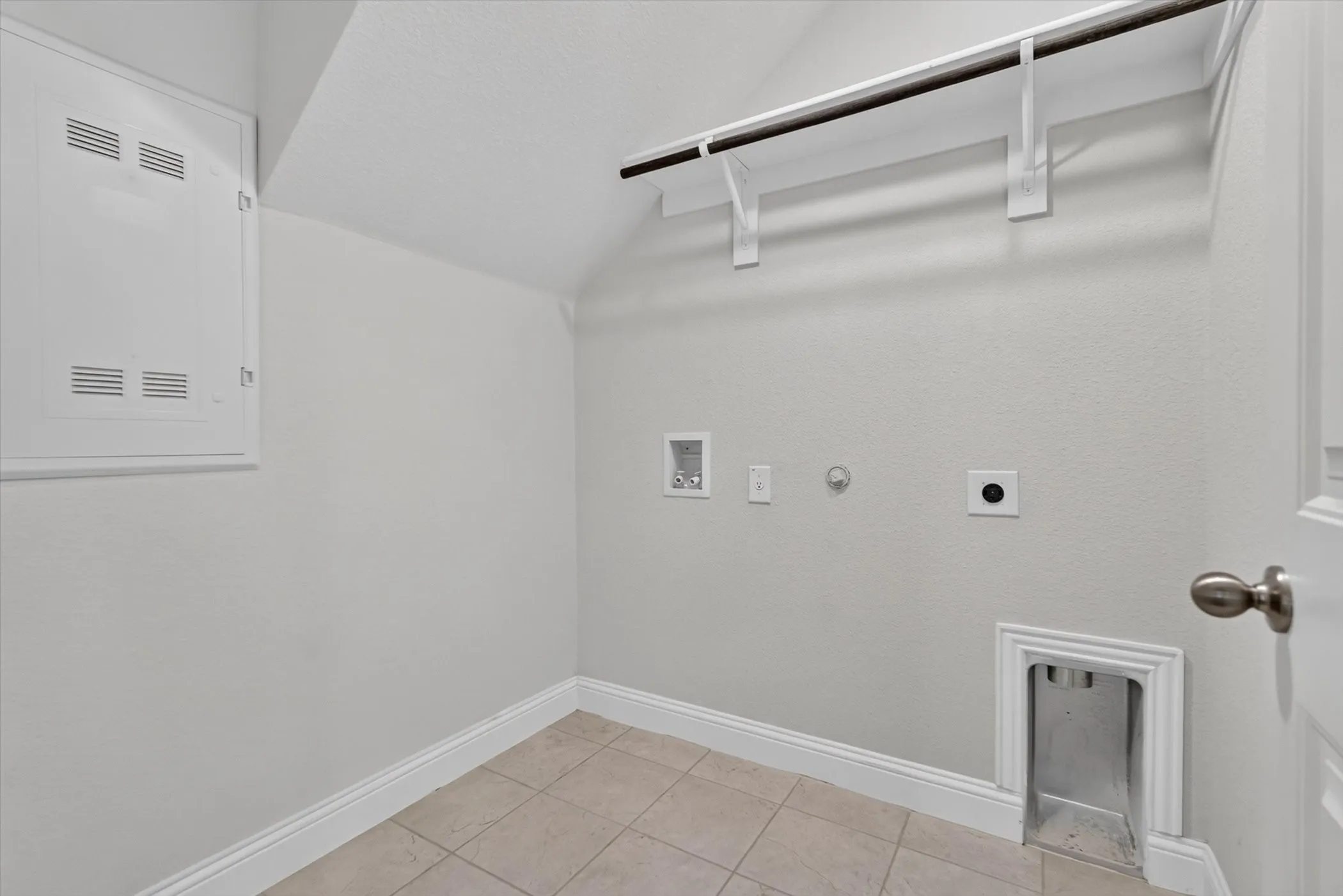 Utility room featuring light-colored tile flooring, white baseboards, and a built-in hanging rod