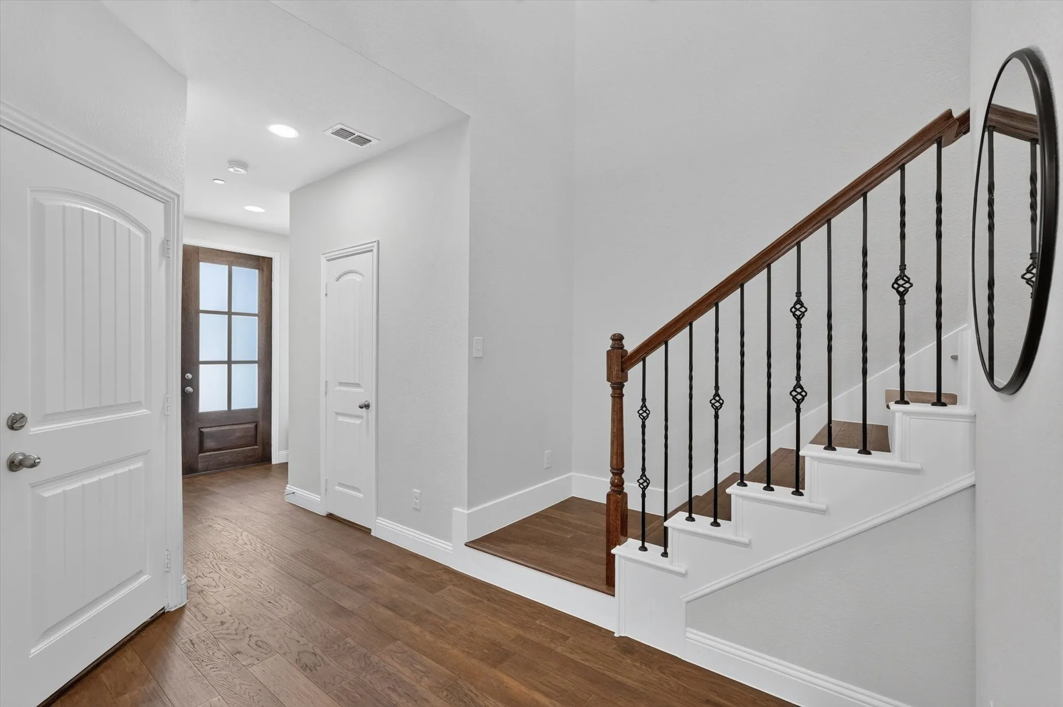 Entryway featuring wood-finish flooring, a dark wood front door with glass panels, and recessed lighting