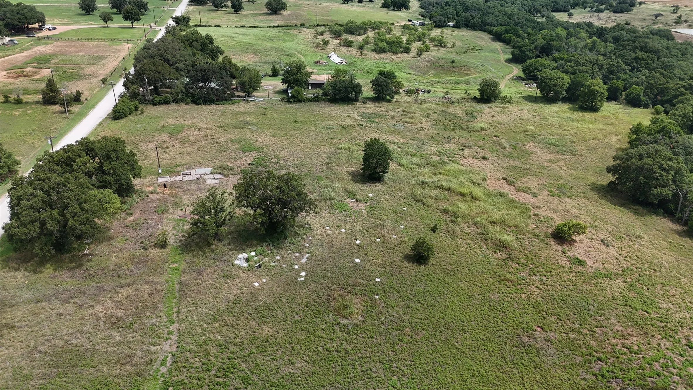 Expansive rural acreage featuring varied topography, mature trees, and existing concrete foundations