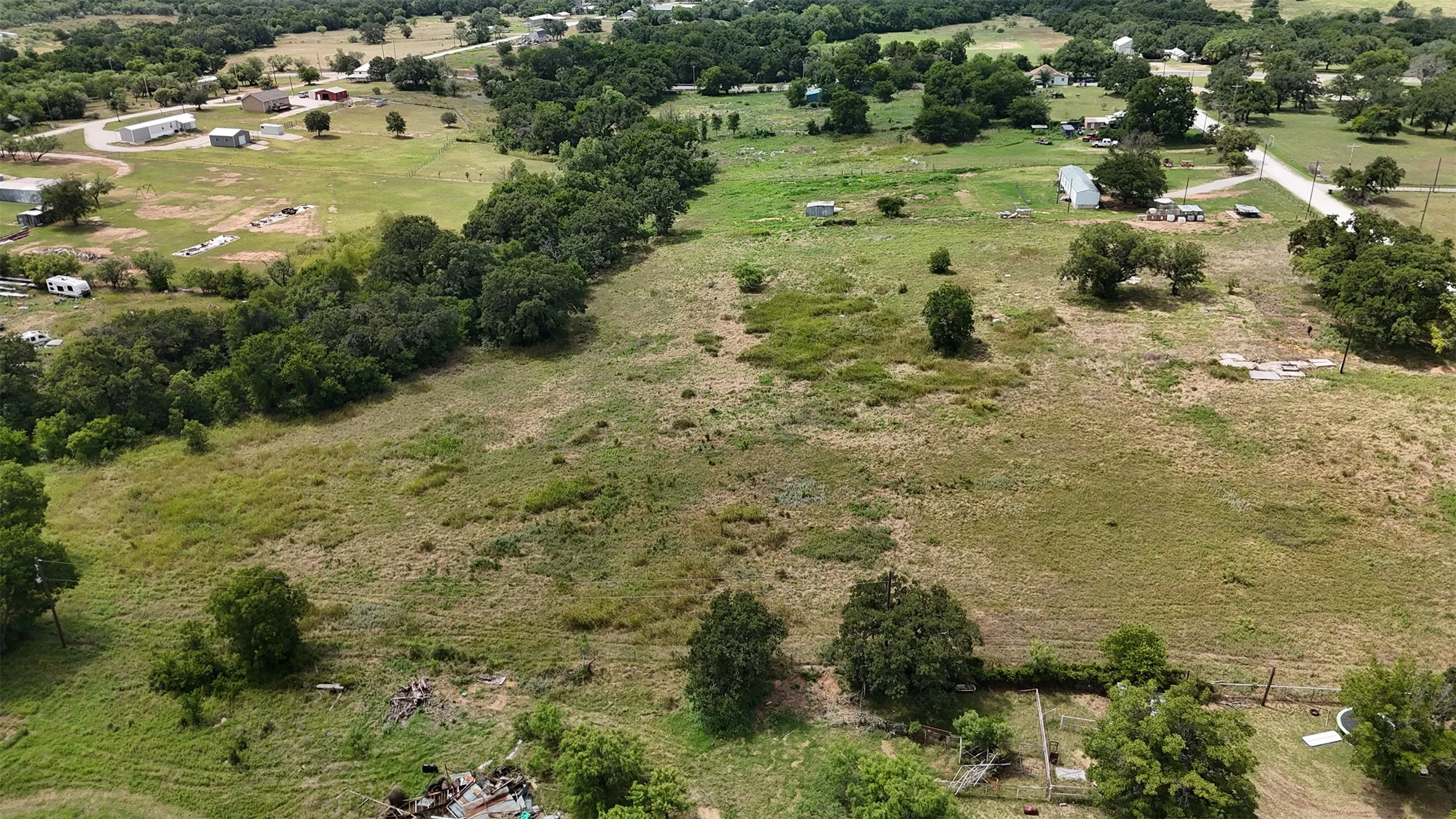 Expansive undeveloped land with varied natural ground cover and scattered mature trees